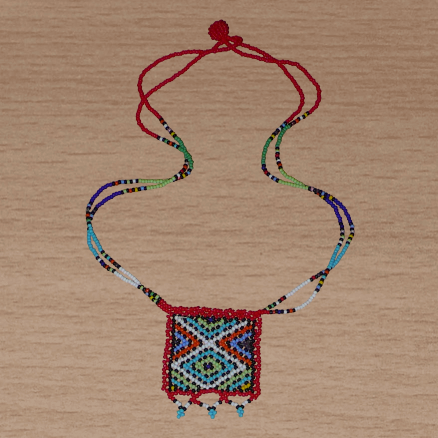 Collier africain traditionnel zoulou avec pendentif carré à motifs ethniques en perles de rocaille rouges et multicolores.