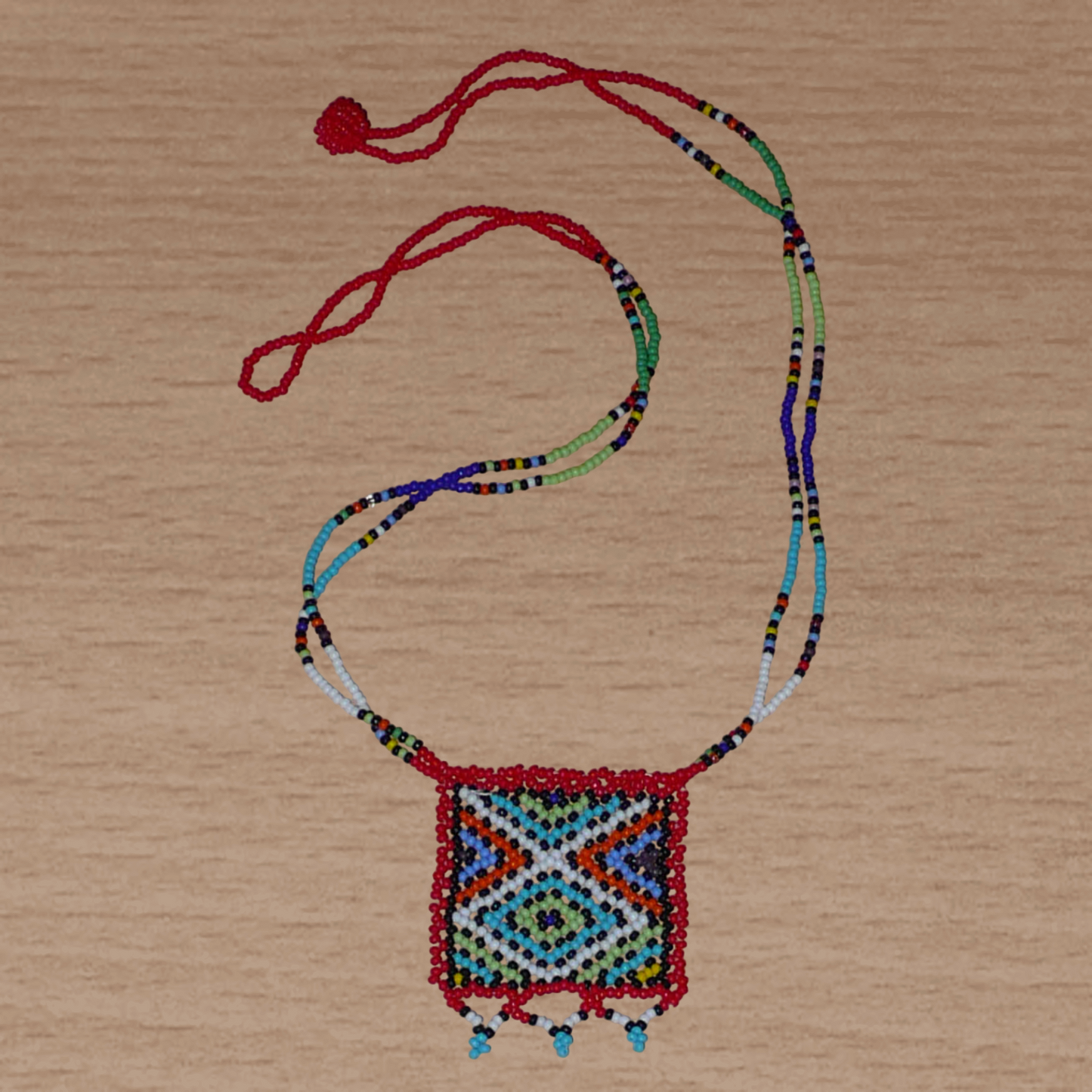 Collier africain traditionnel zoulou avec pendentif carré à motifs ethniques en perles de rocaille rouges et multicolores.