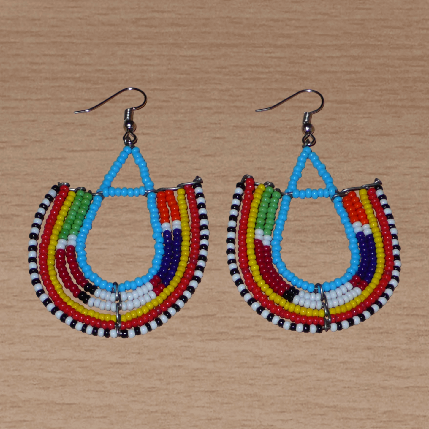 Boucles d'oreilles africaines traditionnelles à motifs ethniques Massai composées de perles de rocaille bleues et multicolores enfilées sur des fils de fer montés en forme d'ancres.
Ces boucles d'oreilles colorées au style exotique tribal chic mesurent 7.5 cm de long et 4.5 cm de large, elles se portent avec des crochets en acier inoxydable sur des oreilles percées.