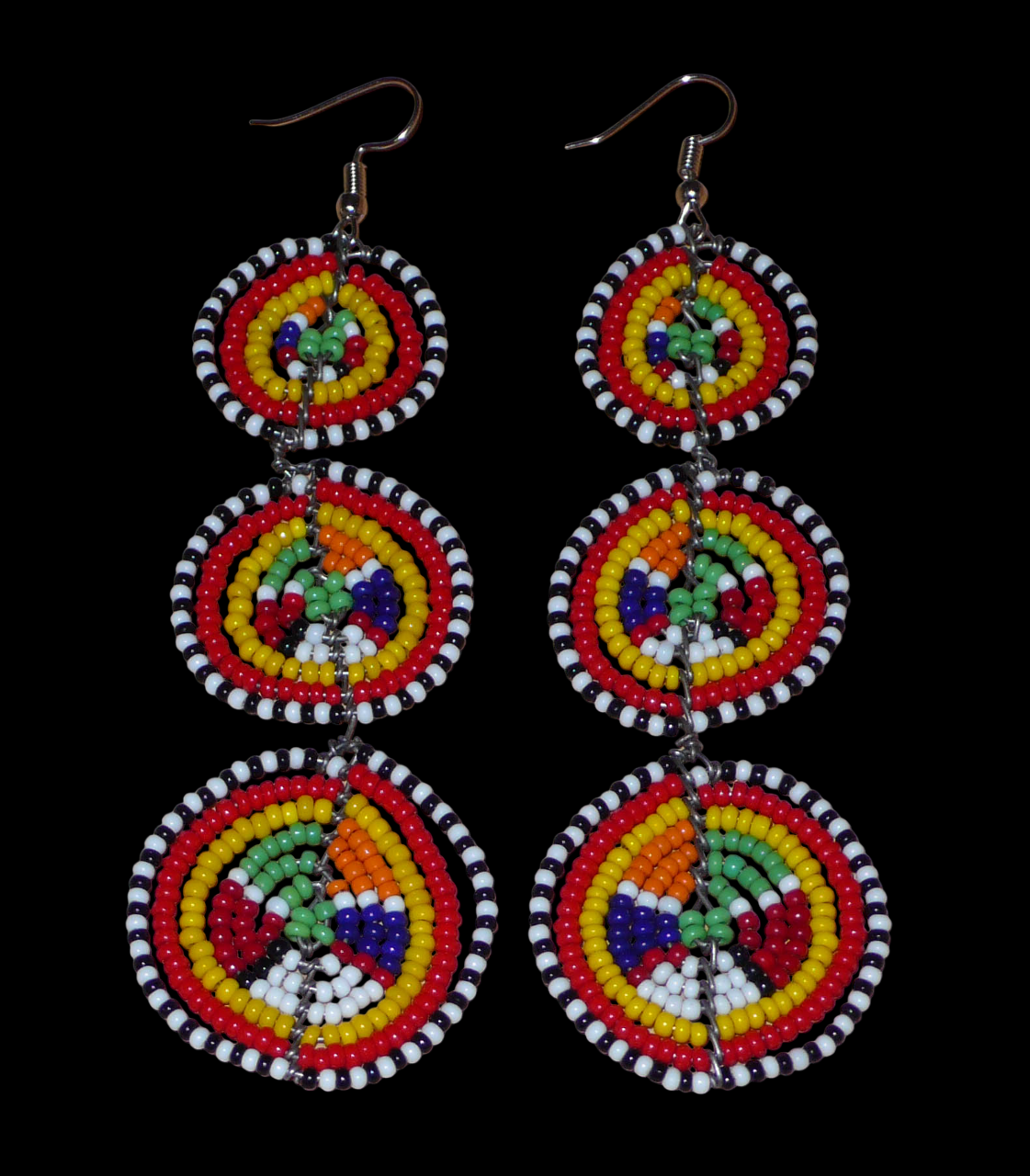 Affirmez votre style avec ces boucles d'oreilles africaines traditionnelles de confection artisanale Massai, évoquant le style afro chic des années 70. Elles se composent de perles de rocaille multicolores enfilées sur des fils de fer montés en forme de trois cercles superposés. Ces boucles d'oreilles mesurent 11 cm de long et 3.5 cm de large ; elles se portent avec des crochets en acier inoxydable sur des oreilles percées.