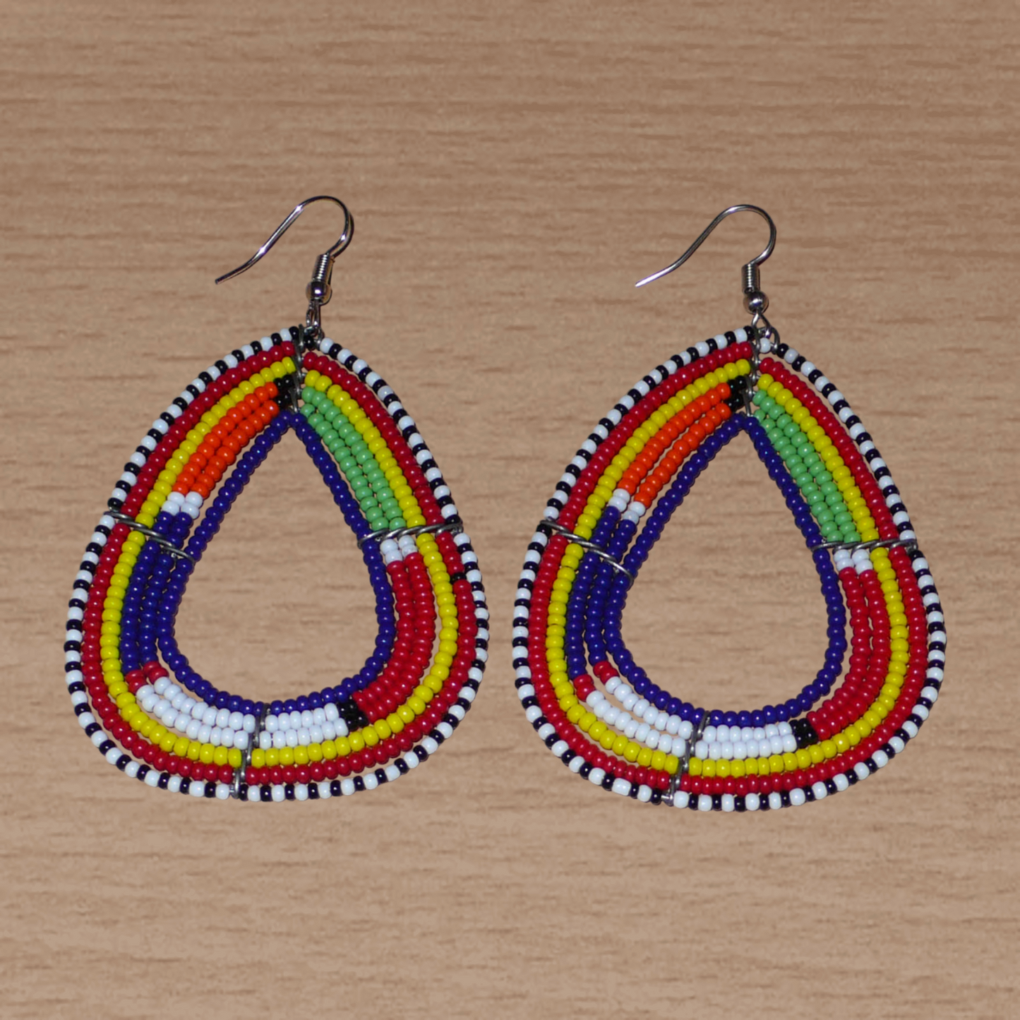 Longues boucles d'oreilles africaines traditionnelles Massai en perles de rocaille bleu foncé et multicolores glissées sur six rangées de fils de fer montés en forme de triangles. Elles mesurent 8,5 cm de long et 5 cm de large et se portent sur des oreilles percées.
