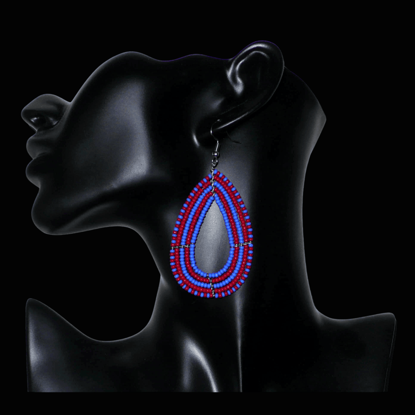 Boucles d'oreilles kenyanes bicolores rouges et bleues en forme de gouttes faites de perles de rocailles. Elles mesurent 8,5 cm de long et 4 cm de large et se portent sur des oreilles percées.