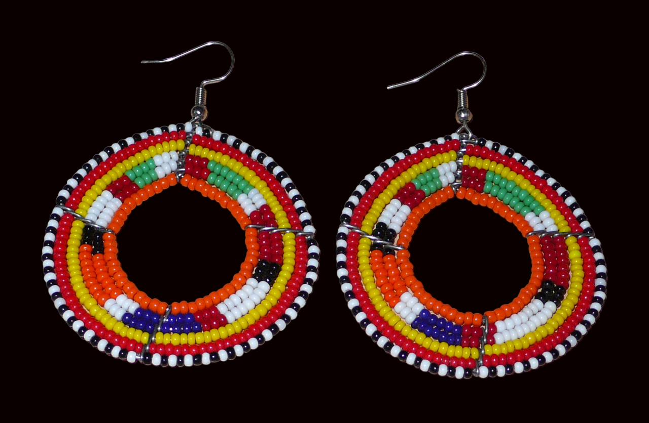 Boucles d'oreilles africaines Massai aux accents afro chic des années 70 composées de perles de rocaille orange et multicolores glissées sur des structures circulaires en fils de fer. De taille moyenne, elles mesurent 7 cm de long et 5 cm de large, et se portent sur des oreilles percées.