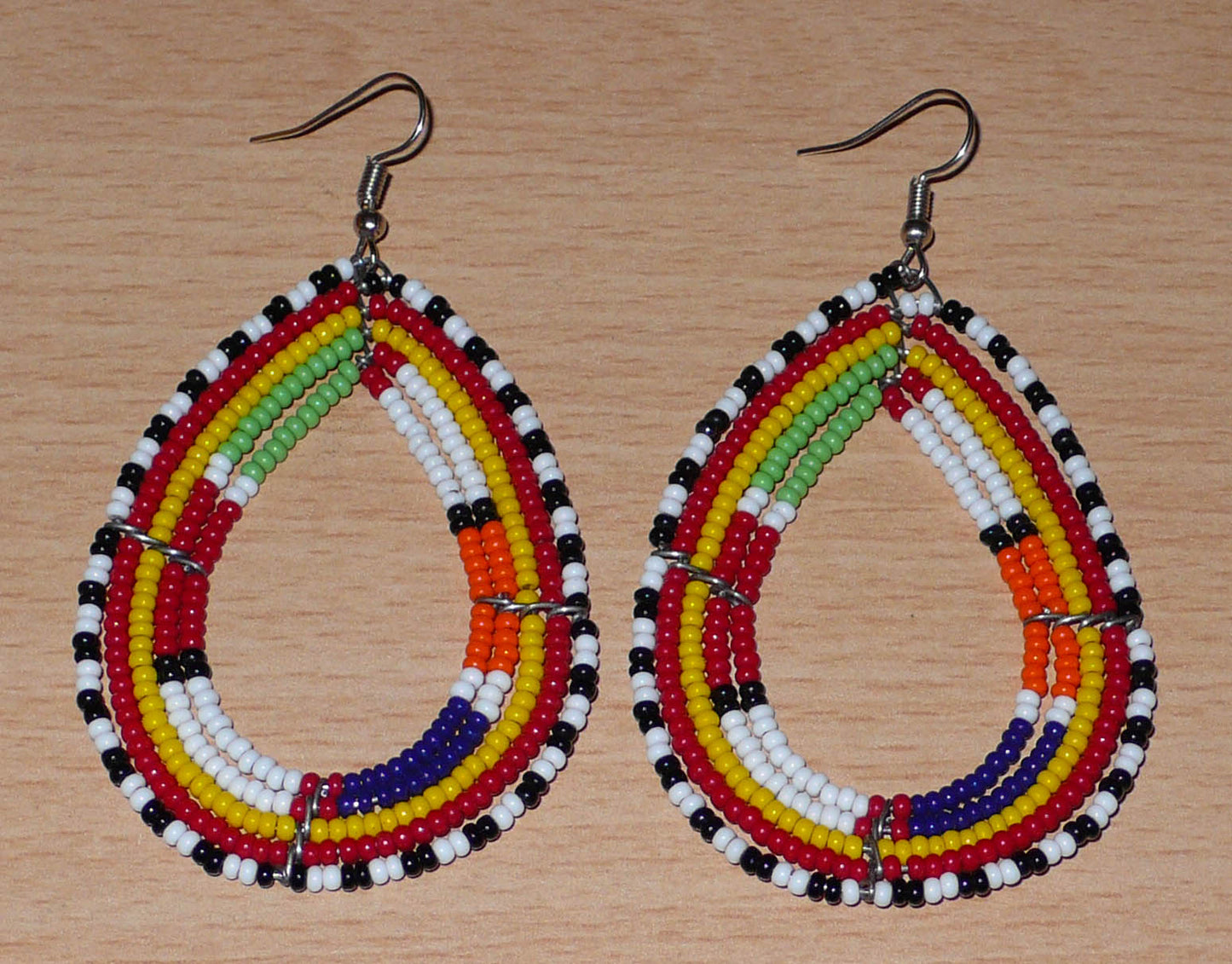Boucles d'oreilles africaines ethniques Massai en perles de rocaille multicolores montées en forme de gouttes. Ces boucles d'oreilles colorées mesurent 8,5 cm de long et 4,5 cm de large et se portent avec des crochets en acier inoxydable sur des oreilles percées.