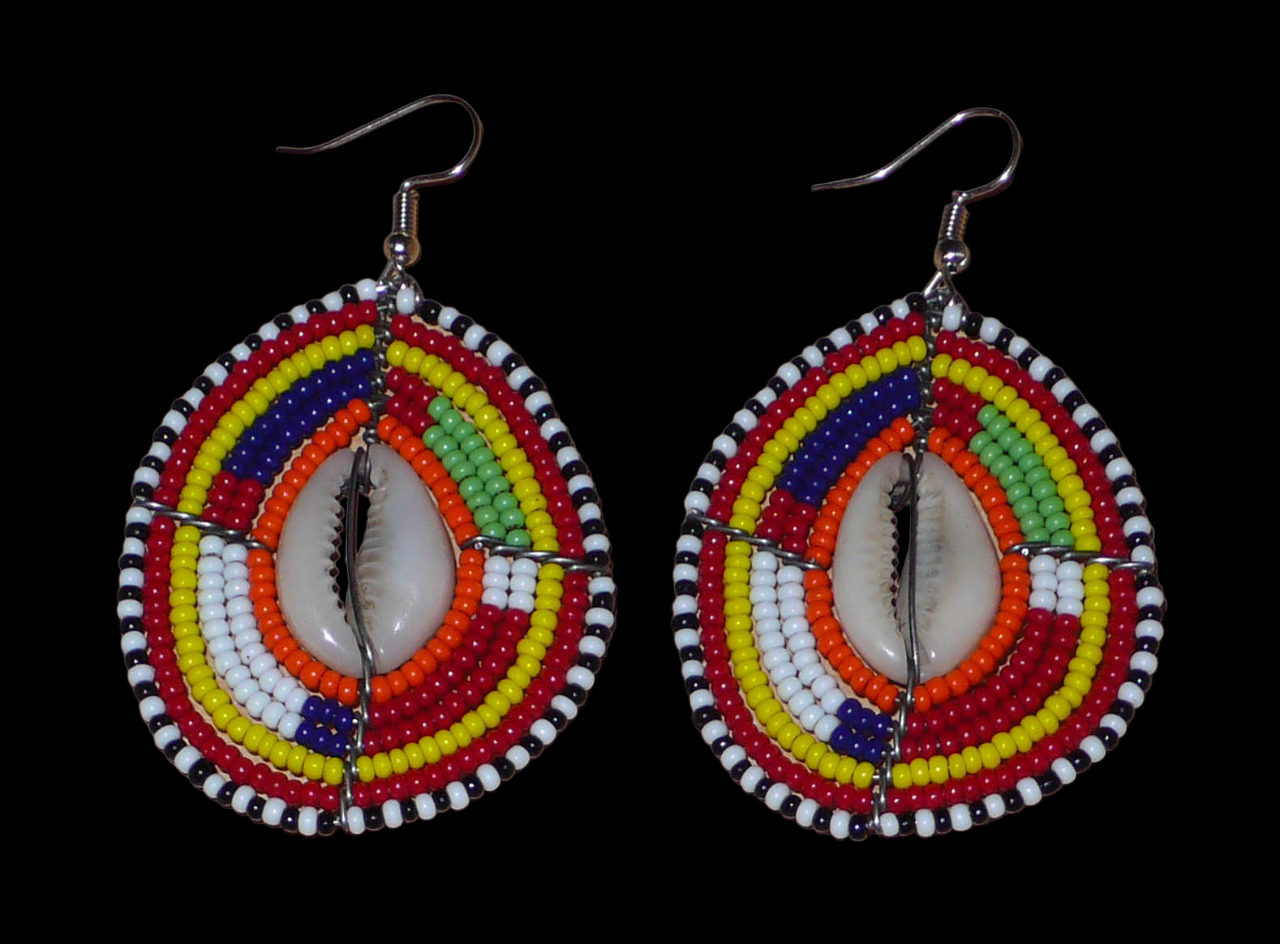 Boucles d'oreilles africaines à motifs ethniques composées de perles et de coquillages montés en forme de boucliers Massai. Elles mesurent 7 cm de long et 4 cm de large et se portent sur des oreilles percées.
