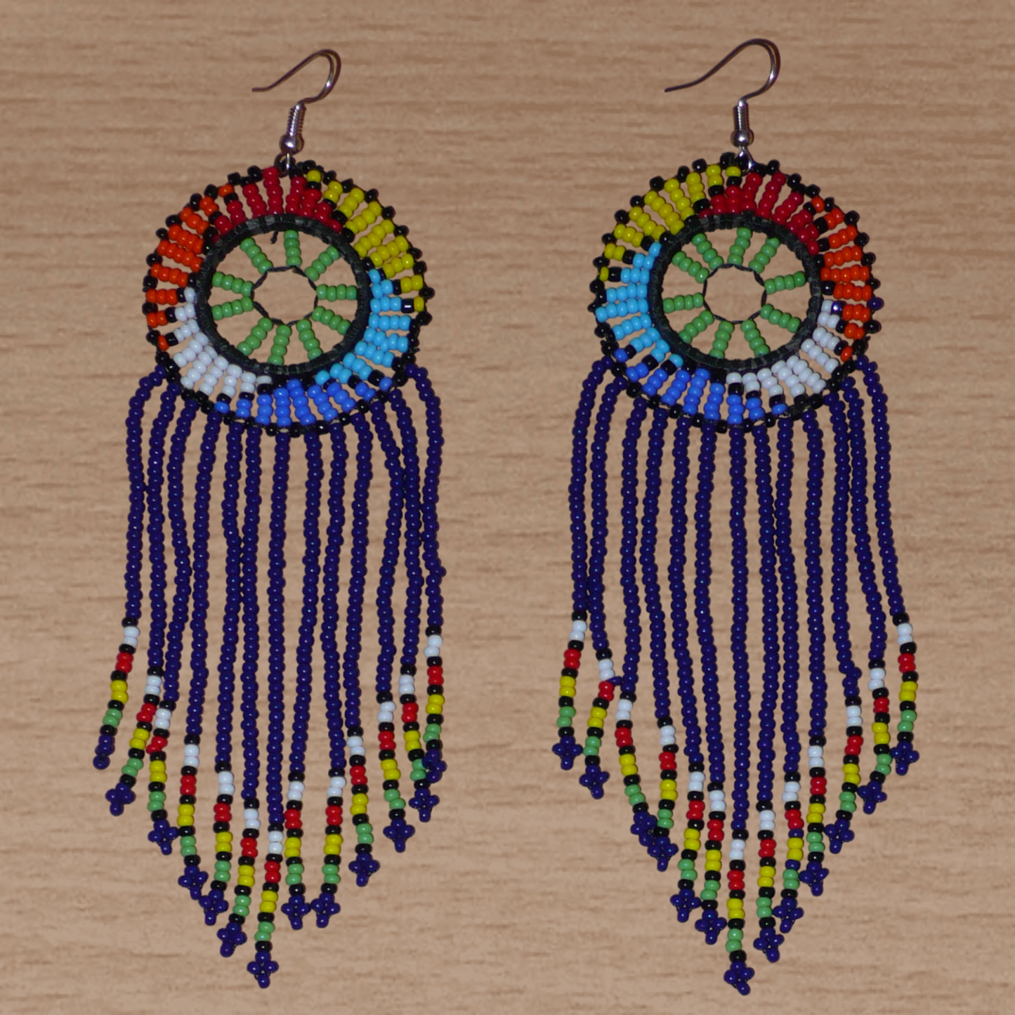 Boucles d'oreilles ethniques à franges fabriquées en Afrique du Sud composées de perles de rocaille bleu foncé, vertes et multicolores ; elles mesurent 14.5 cm de long et 4.5 cm de large.