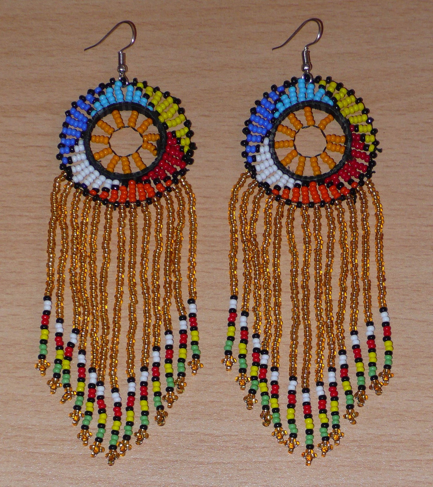 Boucles d'oreilles sud-africaines à franges et motifs traditionnels composées de perles de rocaille translucides dorées et multicolores. Elles mesurent 14,5 cm de long et 4,5 cm de large.