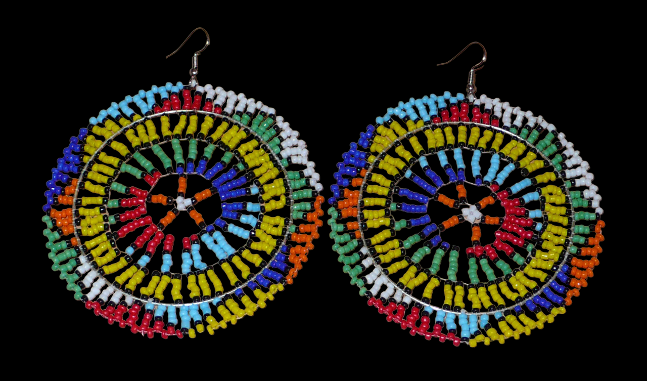 Boucles d'oreilles sud-africaines rondes au style afro chic des années 70. Elles se composent de perles de rocaille multicolores enfilées sur des fils de nylon fixés sur des structures circulaires. Surdimensionnées, elles mesurent 10 cm de long et 8,5 cm de large, et se portent sur des oreilles percées.