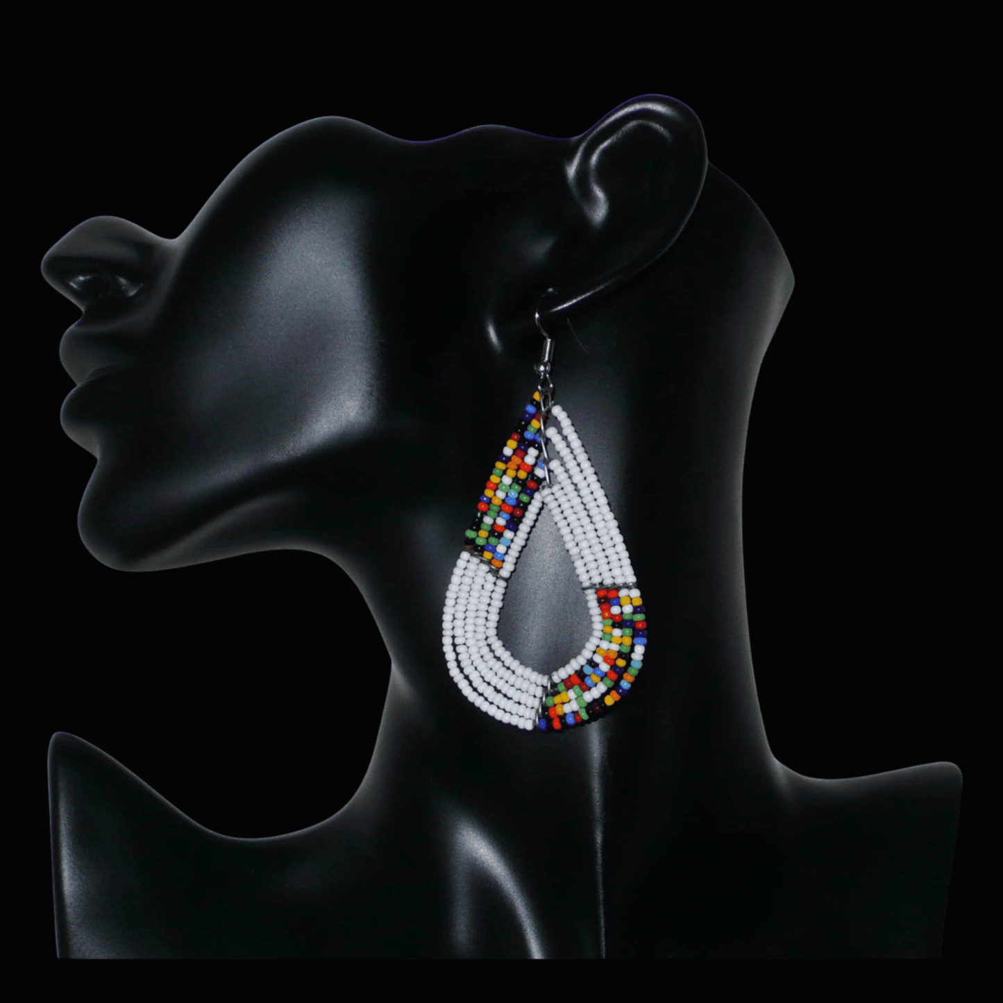 Boucles d'oreilles africaines multi-rangs blanches et multicolores aux accents évoquant le style bohème des années 70. Fabriquées au Kenya, elles se composent de perles de rocaille blanches et d'un mélange de perles multicolores glissées sur cinq rangées de fils de fer en forme de gouttes légèrement triangulaires. Ces boucles d'oreilles mesurent 8 cm de long et 4 cm de large ; elles se portent avec des crochets en acier inoxydable sur des oreilles percées.