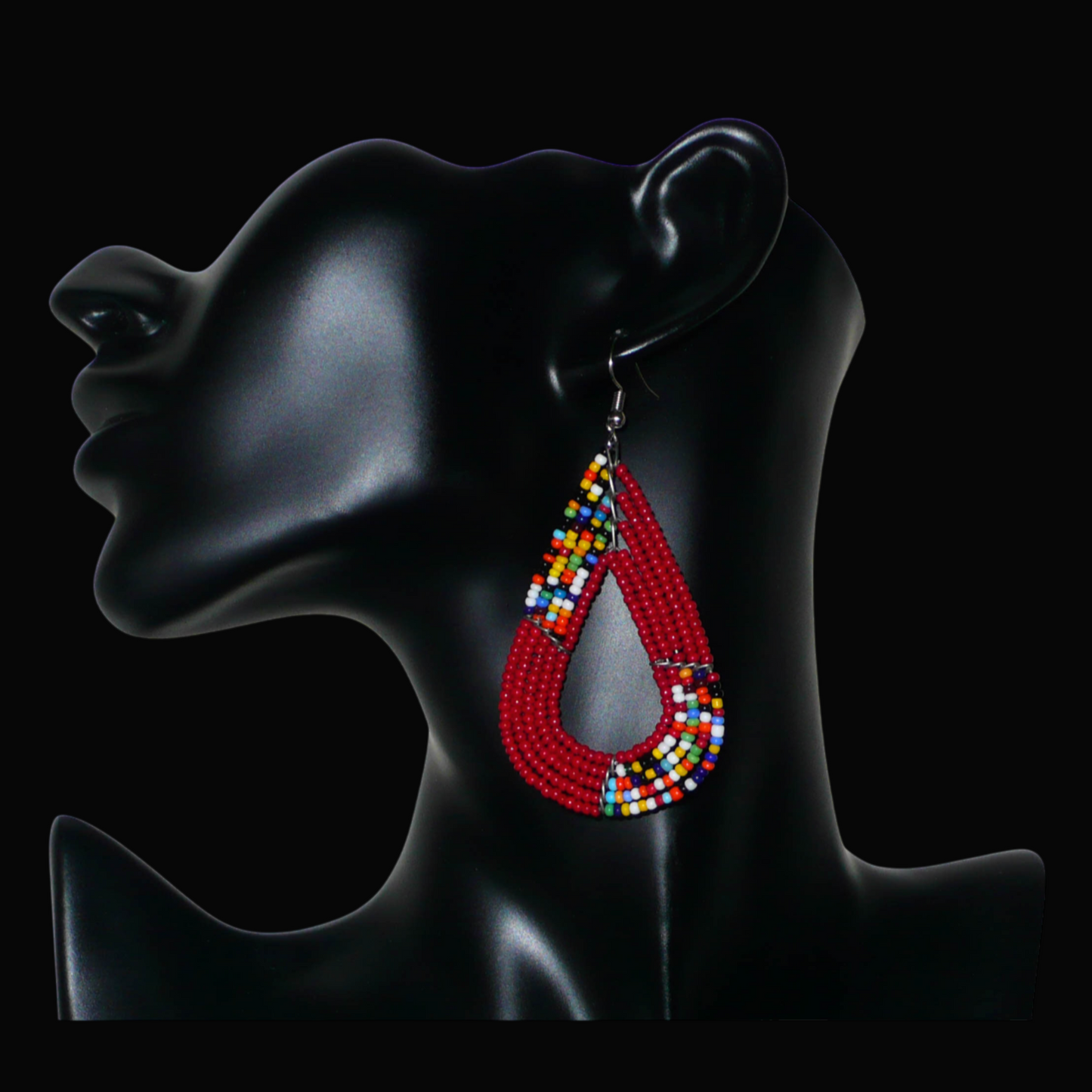 Boucles d'oreilles africaines Massai rouges et multicolores aux accents évoquant le style boho chic des années 70. Confectionnées au Kenya, elles se composent de perles de rocaille rouges et d'un mélange de perles multicolores glissées sur cinq rangées de fils de fer en forme de gouttes légèrement triangulaires. Ces boucles d'oreilles mesurent 8 cm de long et 4 cm de large ; elles se portent avec des crochets en acier inoxydable sur des oreilles percées.