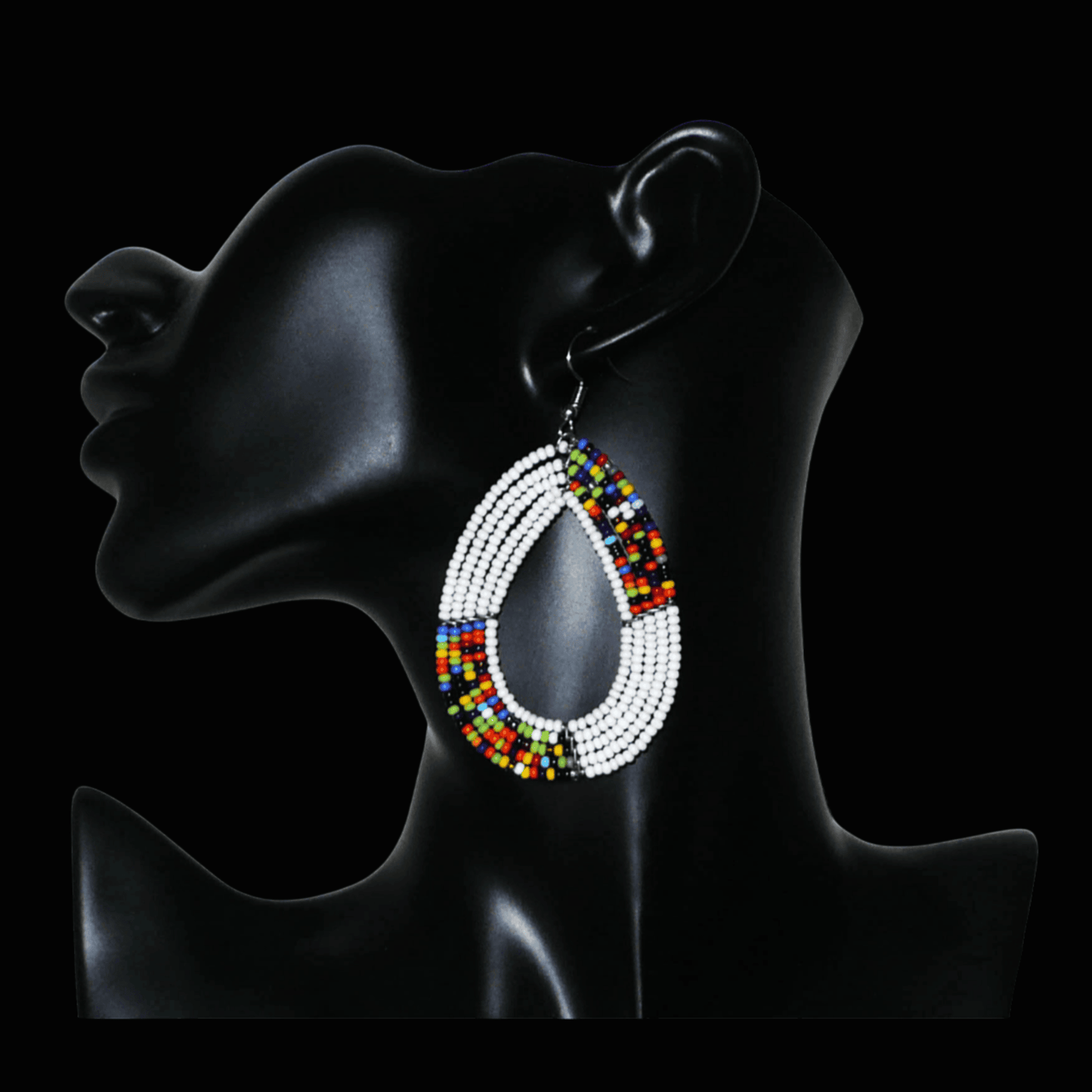 Boucles d'oreilles ethniques fabriquées au Kenya faites de perles de rocaille blanches et multicolores enfilées sur cinq rangées de fils de fer montés en forme de gouttes. Elles mesurent 8 cm de long et 4,5 cm de large et se portent sur des oreilles percées.