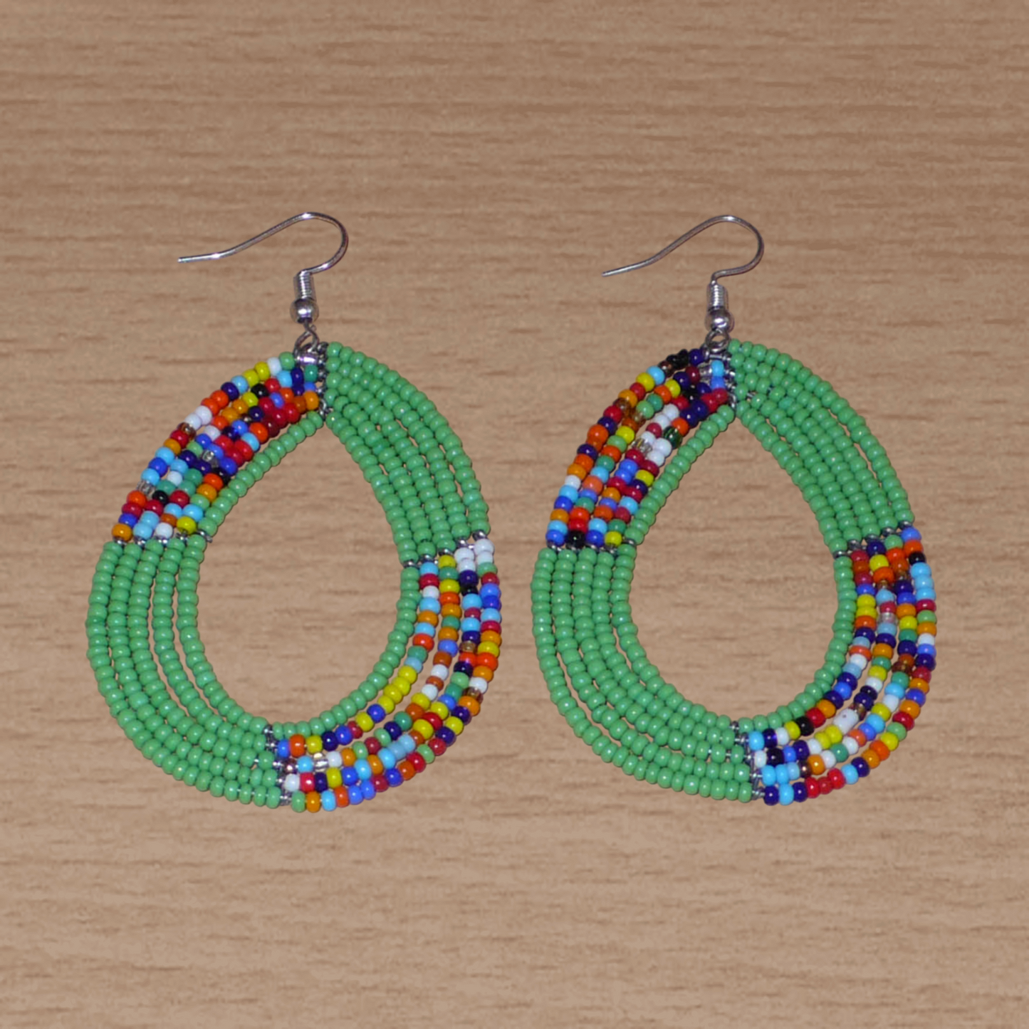 Boucles d'oreilles ethniques multi-rangs composées de perles de rocaille vertes et multicolores montées en forme de gouttes. Elles mesurent 8 cm de long et 4,5 cm de large et se portent sur des oreilles percées.