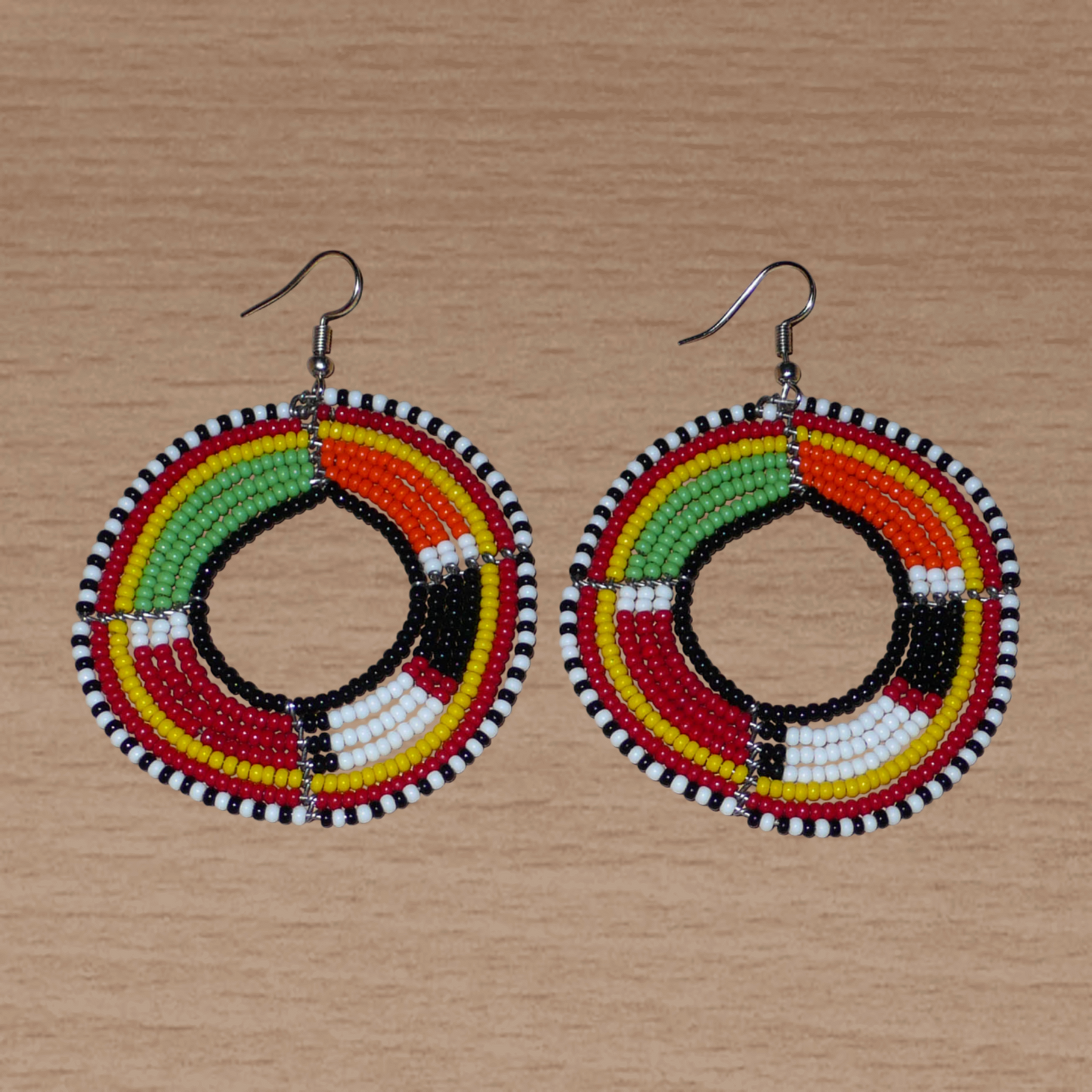 Boucles d'oreilles africaines à motifs ethniques Massai composées de perles de rocaille multicolores montées en forme de cercles. Elles mesurent 7,5 cm de long et 5,5 cm de large et se portent avec des crochets en acier inoxydable sur des oreilles percées.