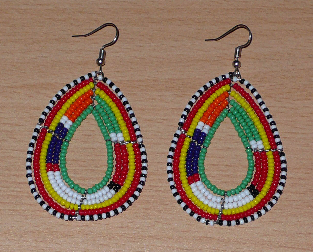 Boucles d'oreilles africaines de tradition Massai en forme de gouttes faites de perles de rocaille vertes et multicolores. Elles mesurent 7,5 cm de long et 4 cm de large, et se portent sur des oreilles percées.