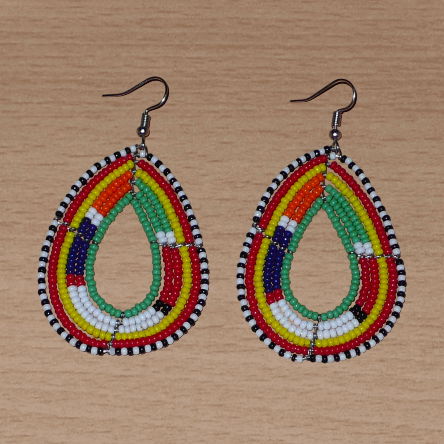 Boucles d'oreilles africaines de tradition Massai en forme de gouttes faites de perles de rocaille vertes et multicolores. Elles mesurent 7,5 cm de long et 4 cm de large, et se portent sur des oreilles percées.