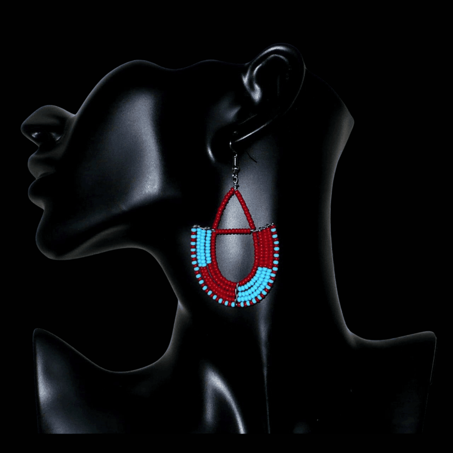 Boucles d'oreilles africaines Massai rouges et bleues composées de perles de rocaille glissées sur des structures géométriques en fils de fer montées en forme d'ancres. Ces boucles d'oreilles bicolores mesurent 7,5 cm de long et 4 cm de large et se portent avec des crochets en acier inoxydable.