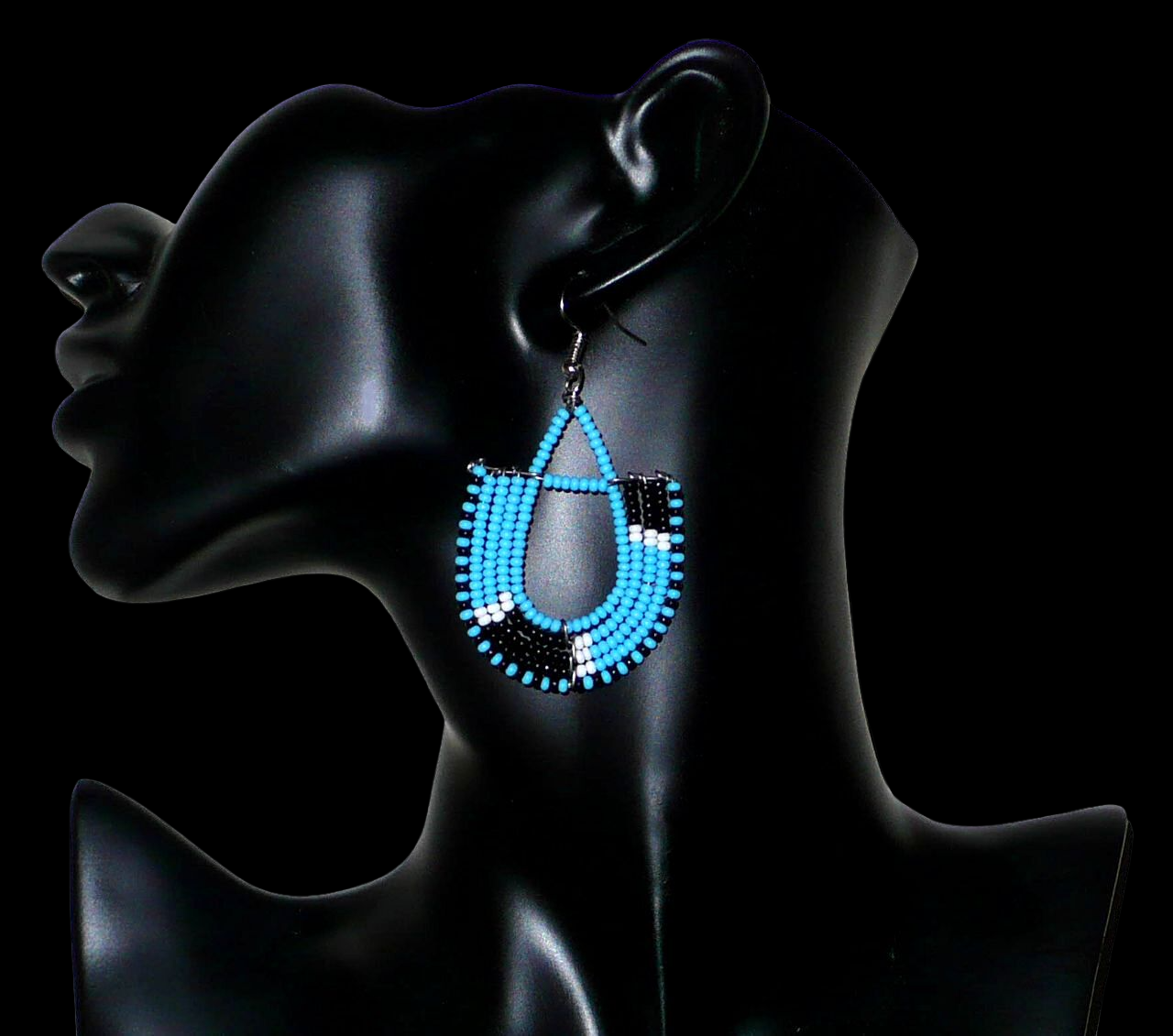 Boucles d'oreilles ethniques tricolores en forme d'ancres composées de perles bleues, noires et blanches. Elles mesurent 7 cm de long et 4 cm de large et se portent sur des oreilles percées.
