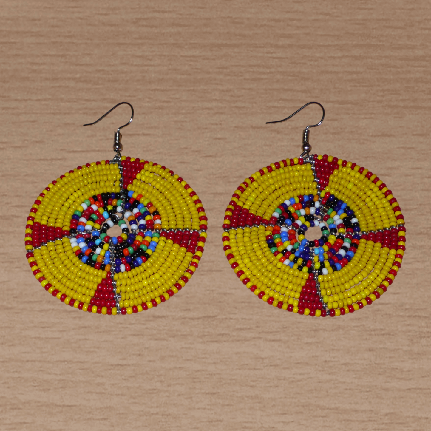 Boucles d'oreilles ethniques kenyanes en perles de rocaille principalement jaunes, puis rouges et multicolores enfilées sur des structures circulaires en fils de fer. Elles mesurent 7.5 cm de long et se portent sur des oreilles percées.