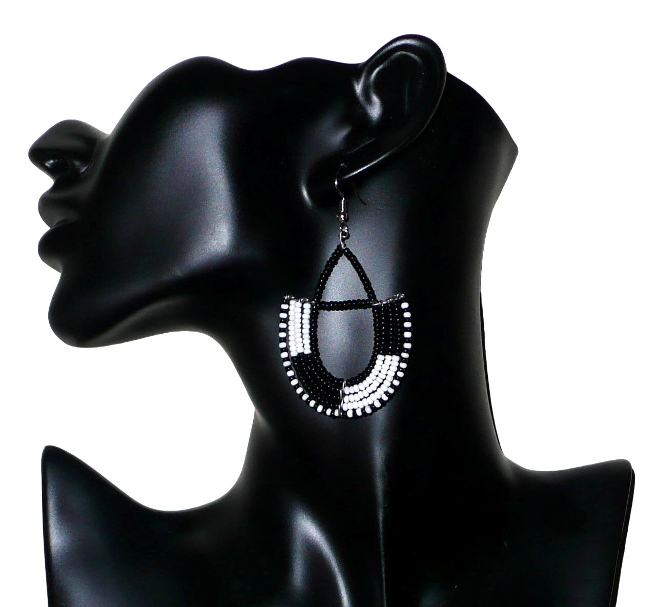 Boucles d'oreilles ethniques Massai chic noires et blanches en forme d'ancres ; elles mesurent 7 cm de long et 4 cm de large et se portent sur des oreilles percées.