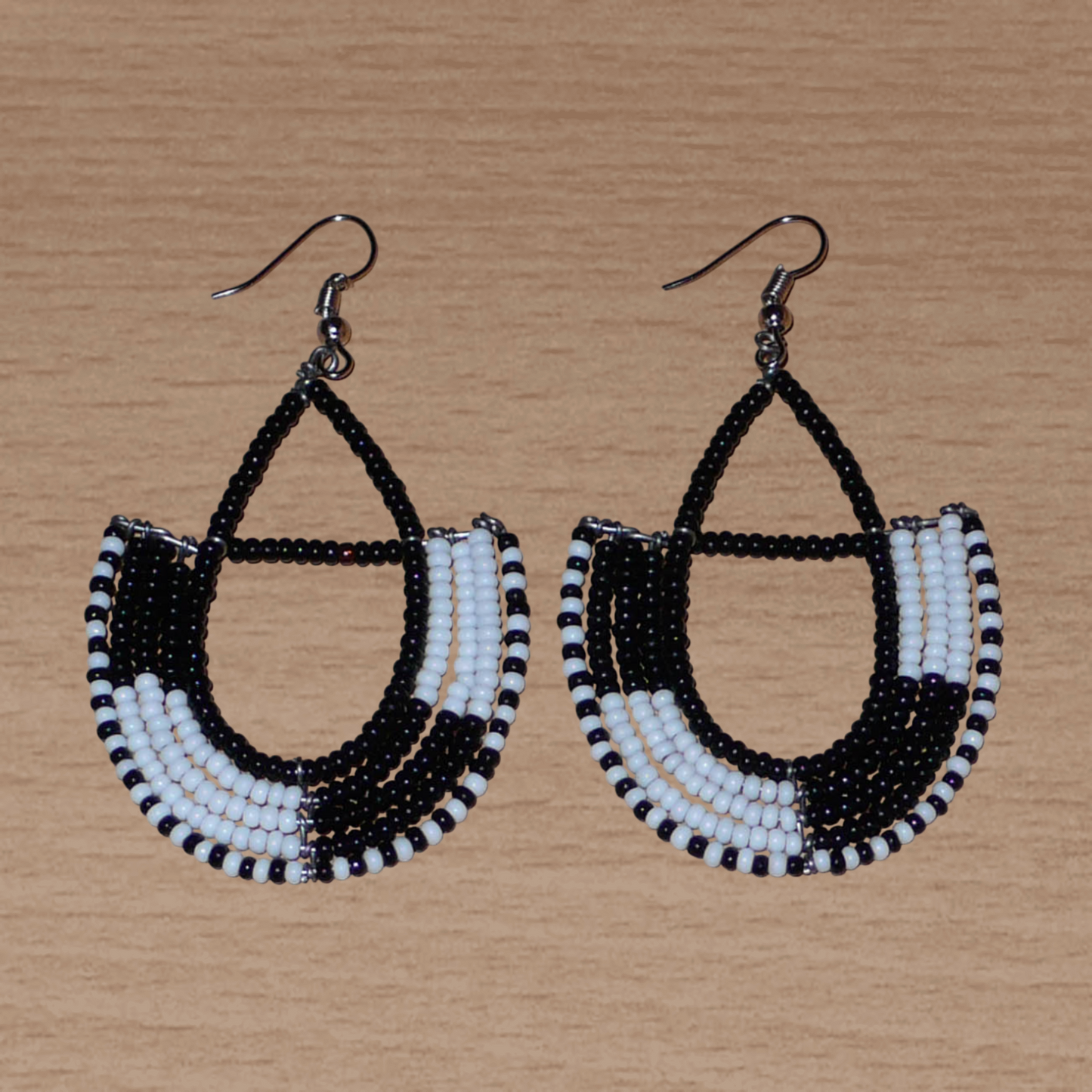 Boucles d'oreilles ethniques Massai chic noires et blanches en forme d'ancres ; elles mesurent 7 cm de long et 4 cm de large et se portent sur des oreilles percées.