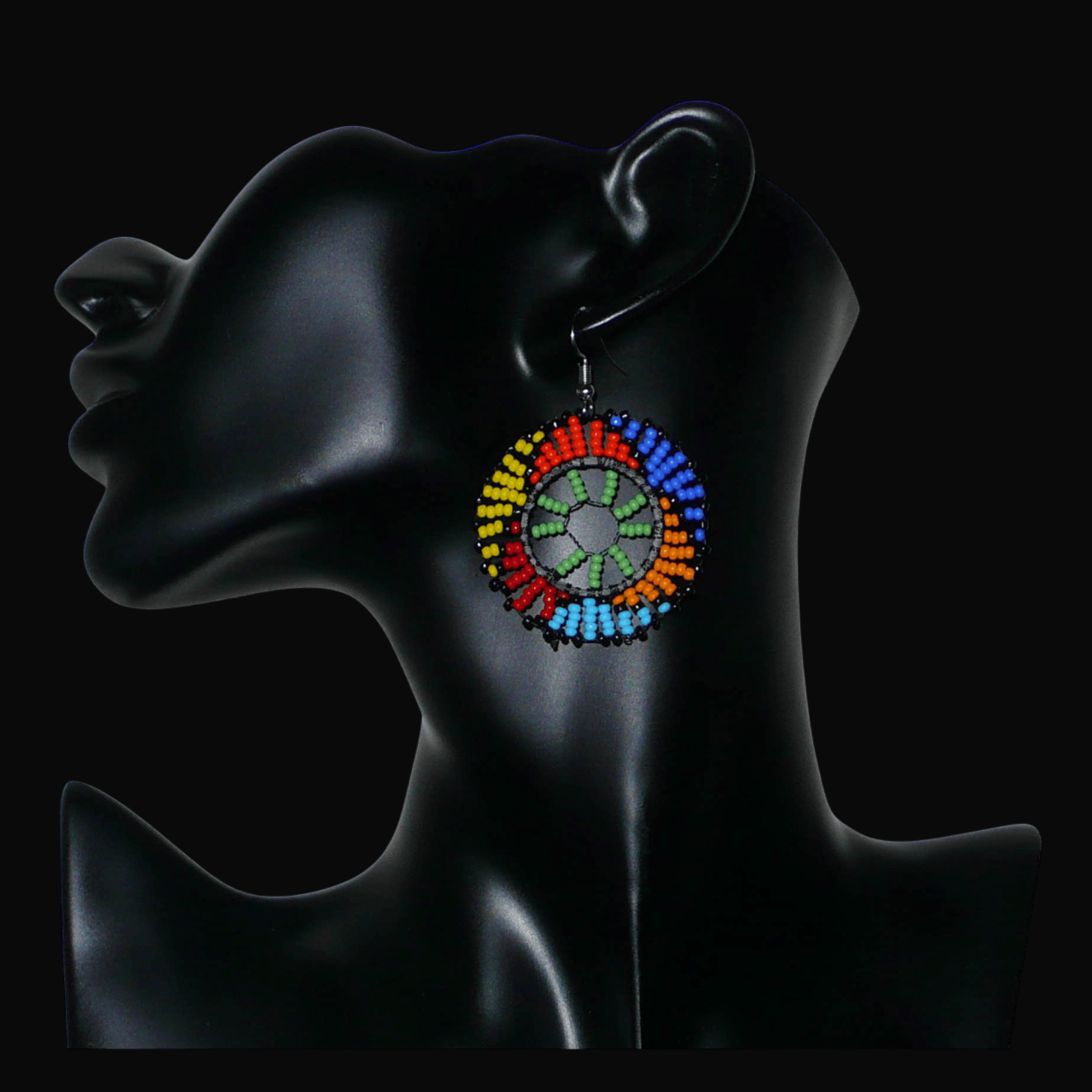 Boucles d'oreilles ethniques rondes à motifs zoulous composées de perles de rocaille vertes et multicolores. De taille moyenne et légères à porter, elles mesurent 6 cm de long et 4 cm de large ; elles se portent avec des crochets en acier inoxydable sur des oreilles percées.
