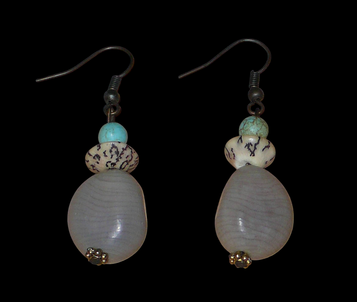 Boucles d'oreilles exotiques composées de perles et de graines de caniques grises. De taille moyenne, elles mesurent 5 cm de long et 1,5 cm de large, et se portent sur des oreilles percées.