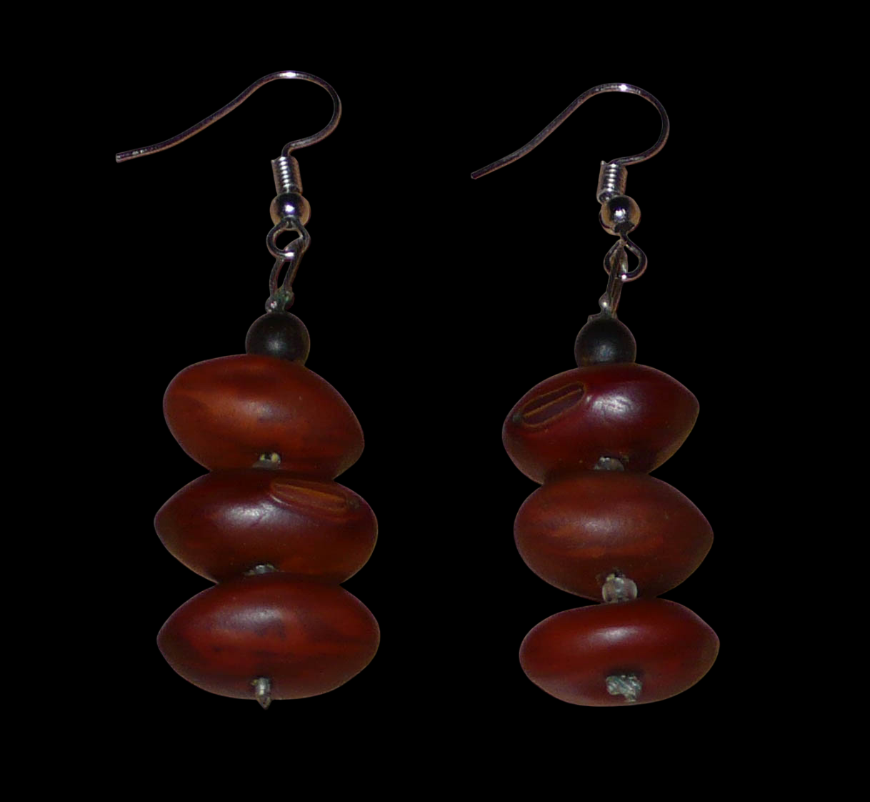 Boucles d'oreilles afro-caribéennes composées de graines organiques issues de la forêt tropicale et de perles de rocailles translucides. De taille moyenne, elles mesurent 6 cm de long et 2 cm de large, et se portent avec des crochets en acier inoxydable sur des oreilles percées.