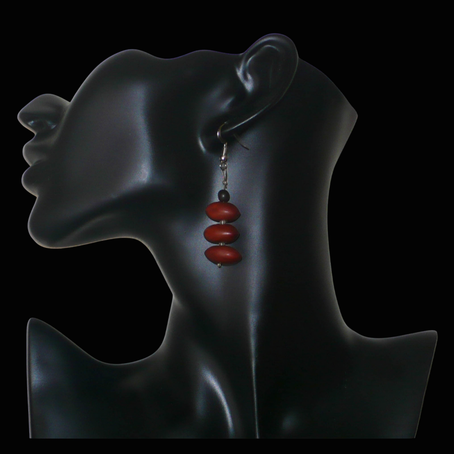 Boucles d'oreilles afro-caribéennes composées de graines organiques issues de la forêt tropicale et de perles de rocailles translucides. De taille moyenne, elles mesurent 6 cm de long et 2 cm de large, et se portent avec des crochets en acier inoxydable sur des oreilles percées.