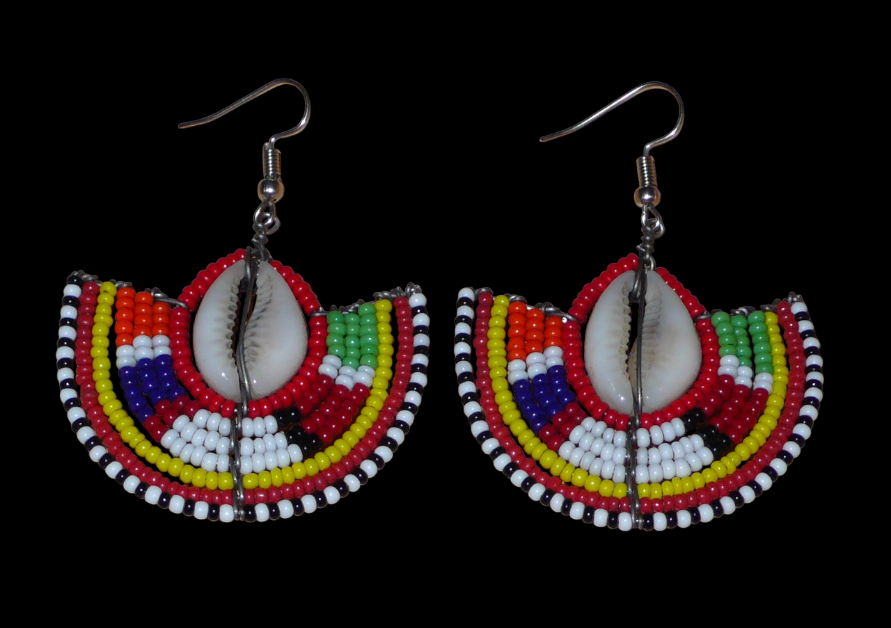 Ajoutez une touche exotique à votre style avec cette jolie paire de boucles d'oreilles africaines issues de l'artisanat traditionnel Massai. Ces boucles d'oreilles ethniques chic se composent de perles de rocaille rouges et multicolores et de coquillages cauris. De taille moyenne, elles mesurent 6 cm de long et 4.5 cm de large, et se portent avec des crochets en acier inoxydable sur des oreilles percées.