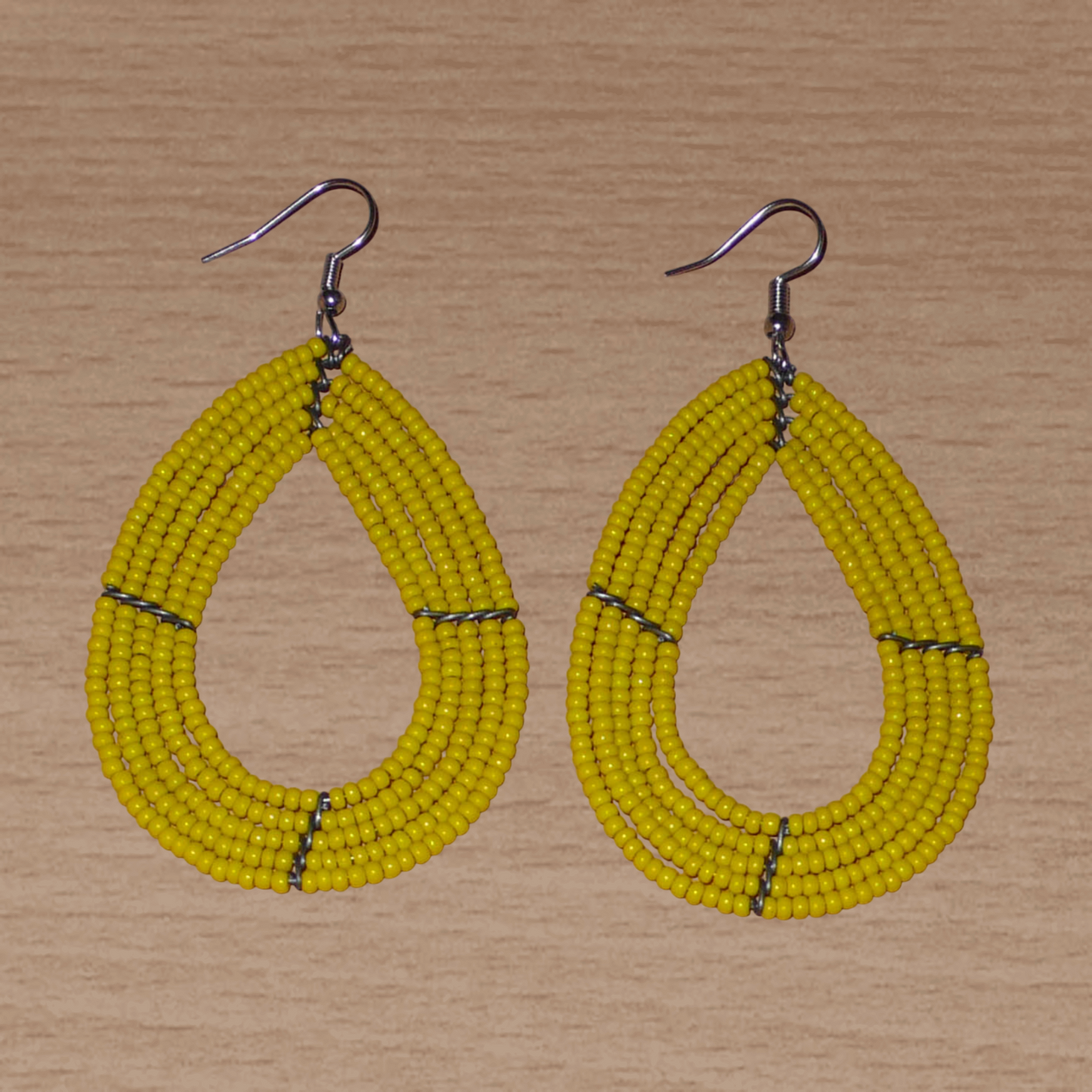Boucles d'oreilles jaunes en forme de gouttes composées de perles de rocaille. Elles mesurent 8 cm de long et 4,5 cm de large, et se portent avec des crochets en acier inoxydable sur des oreilles percées.