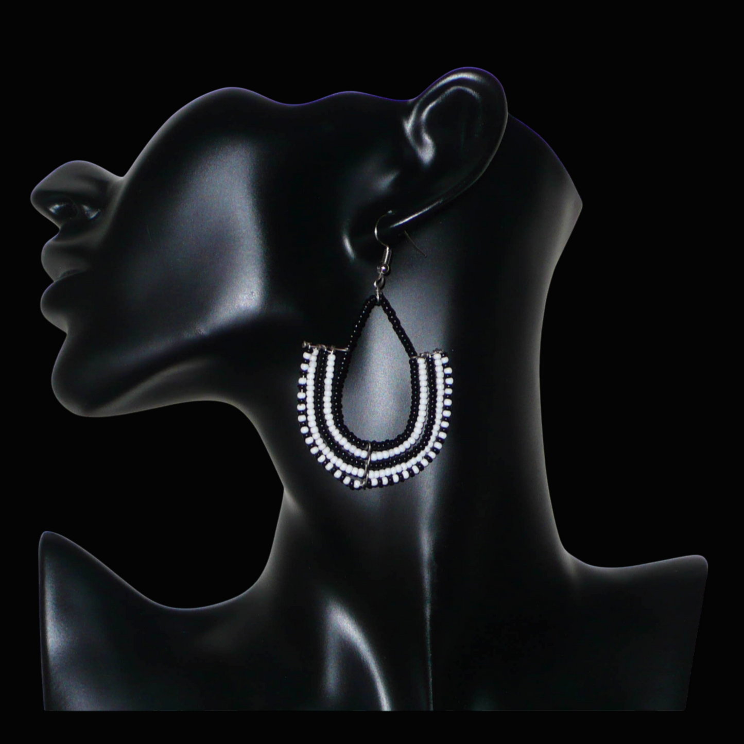 Boucles d'oreilles kenyanes Massai bicolores en forme d'ancres composées de perles de rocaille noires et blanches glissées sur des structures géométriques en fils de fer. De taille moyenne, ces boucles d'oreilles aux accents ethniques afro chic mesurent 7 cm de long et 4 cm de large ; elles se portent avec des crochets en acier inoxydable sur des oreilles percées.