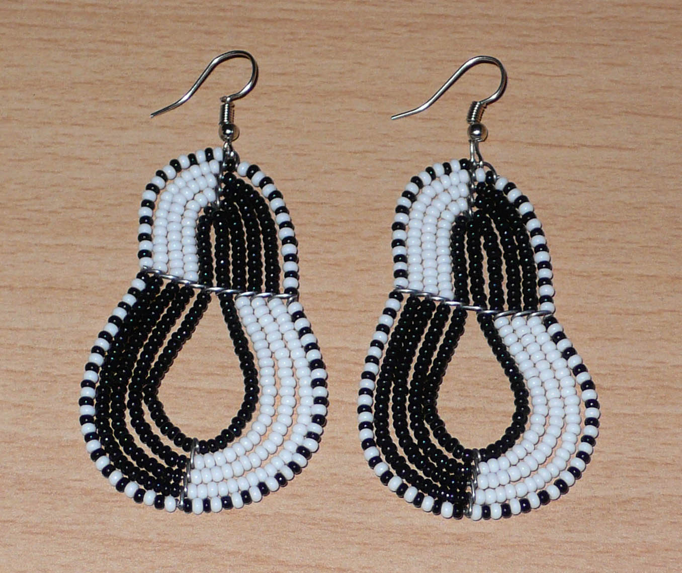 Boucles d'oreilles bicolores composées de perles noires et blanches montées en forme de poires. Elles mesurent 8 cm de long et 3,8 cm de large et se portent sur des oreilles percées.