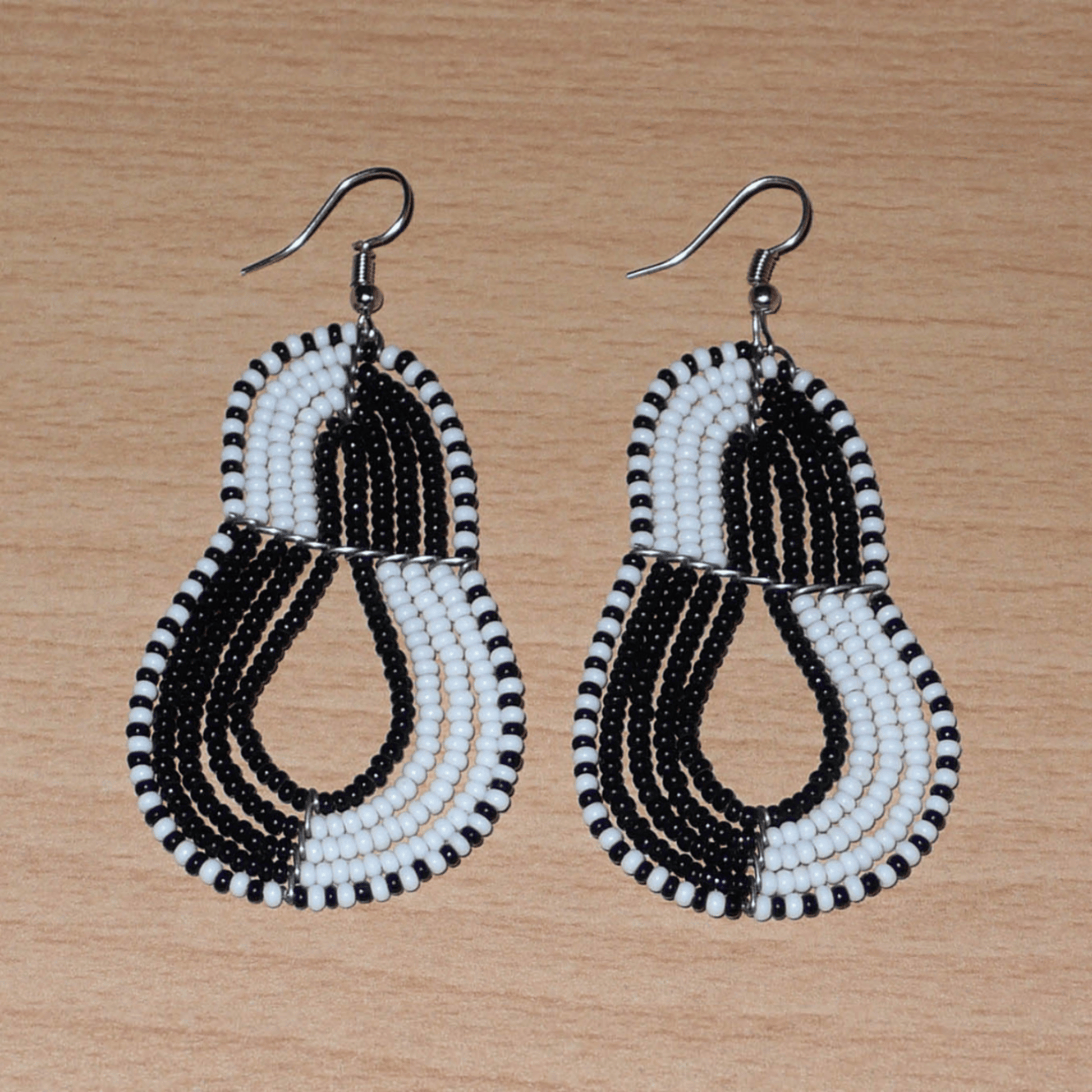 Boucles d'oreilles bicolores composées de perles noires et blanches montées en forme de poires. Elles mesurent 8 cm de long et 3,8 cm de large et se portent sur des oreilles percées.