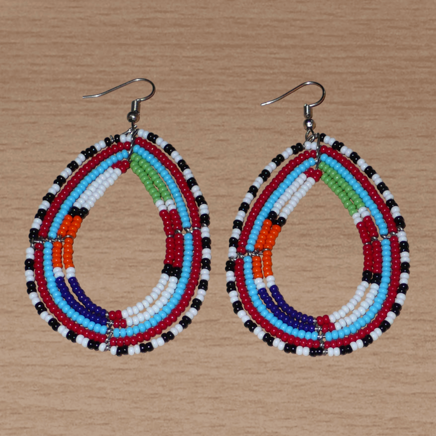 Boucles d'oreilles africaines à motifs ethniques Massai faites de perles de rocaille multicolores montées en forme de gouttes. Elles mesurent 8,5 cm de long et 4,5 cm de large et se portent sur des oreilles percées.