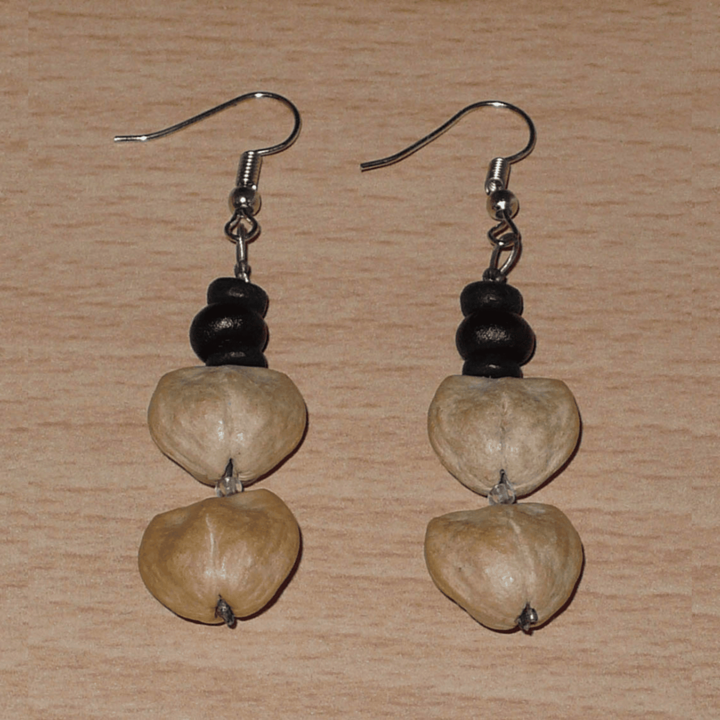 Boucles d'oreilles afro-caribéennes composées de perles de noix de coco et de graines organiques. De taille moyenne, ces boucles d'oreilles aux accents résolument exotiques mesurent 6 cm de long et 1,5 cm de large ; elles se portent avec des crochets en acier inoxydable sur des oreilles percées.