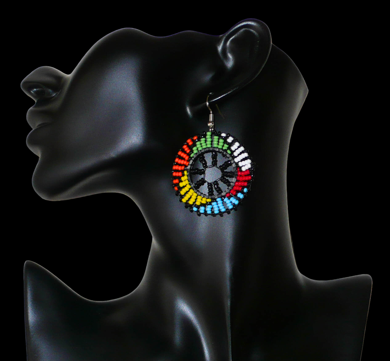 Bijoux traditionnels sud-africains. Boucles d'oreilles ethniques rondes à motifs zoulous composées de perles de rocaille noires et multicolores. De taille moyenne et légères à porter, elles mesurent 6 cm de long et 4 cm de large. Elles se portent avec des crochets en acier inoxydable sur des oreilles percées. Timeless Fineries