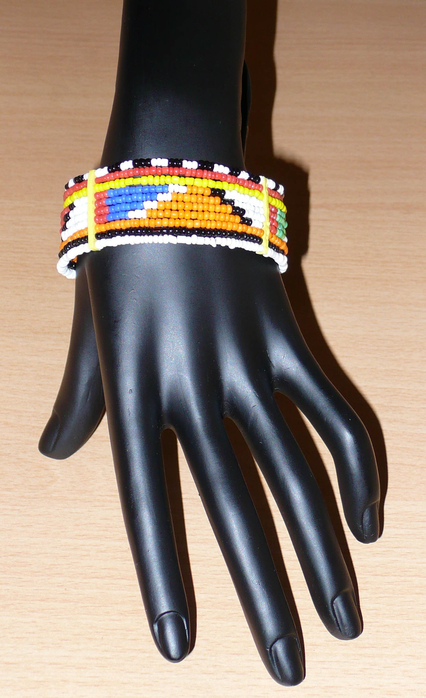 Bracelet africain Massai traditionnel composé de dix rangées de perles de rocaille multicolores enfilées sur des fils de fer fixés sur des charnières en plastique ; il se ferme avec deux crochets.