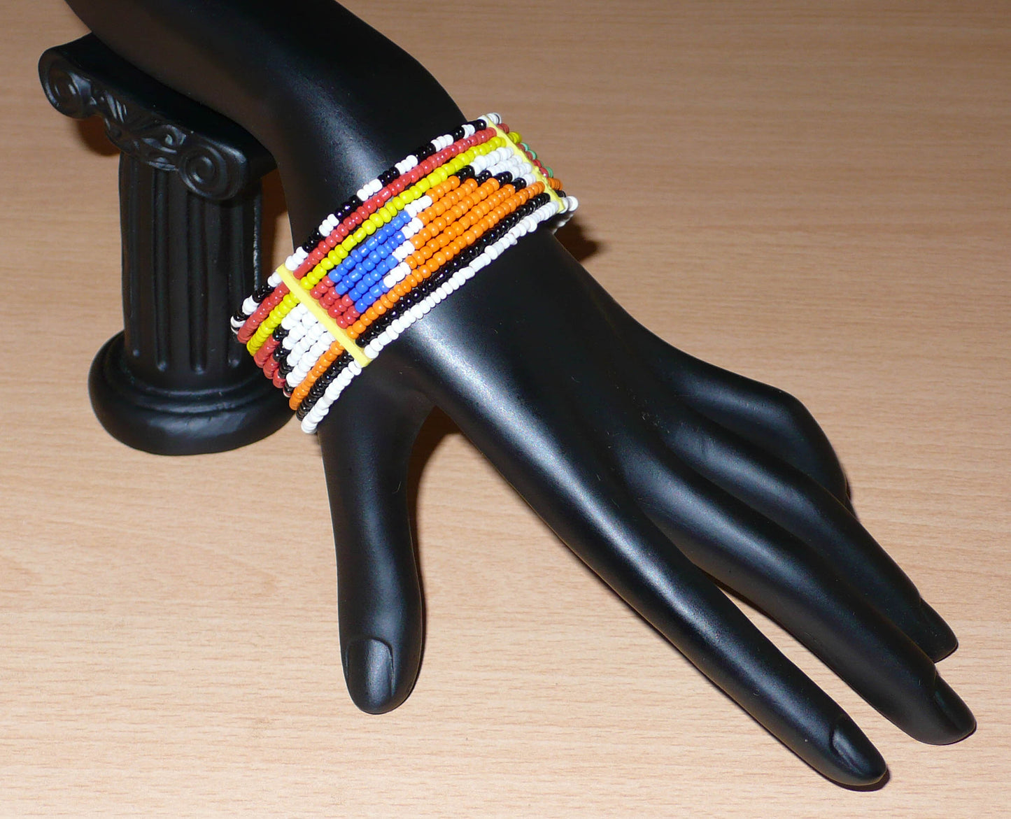 Bracelet africain Massai traditionnel composé de dix rangées de perles de rocaille multicolores enfilées sur des fils de fer fixés sur des charnières en plastique ; il se ferme avec deux crochets.