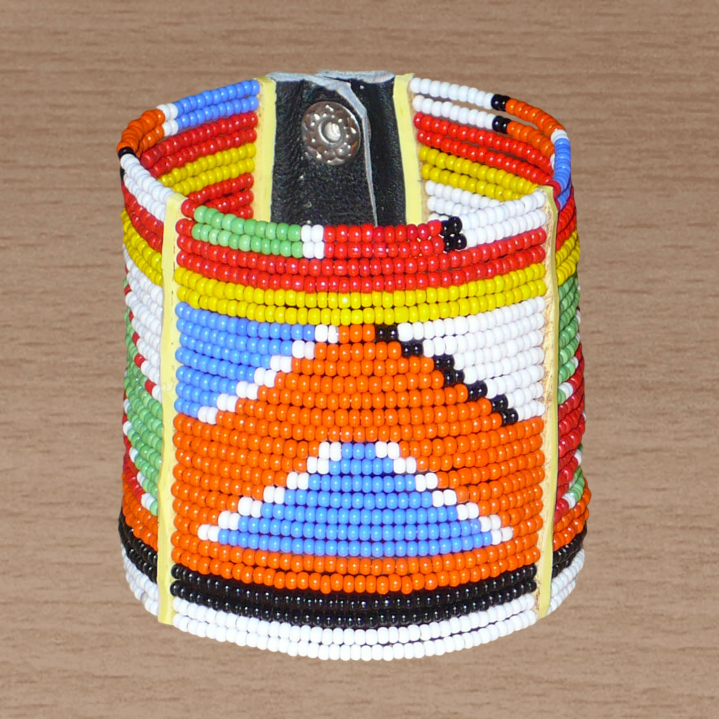 Bracelet africain traditionnel composé de perles de rocaille aux couleurs et motifs ethniques Massai enfilées sur vingt-six rangées de fils de fer fixés sur des charnières en plastique. Il se ferme avec des boutons pressions.