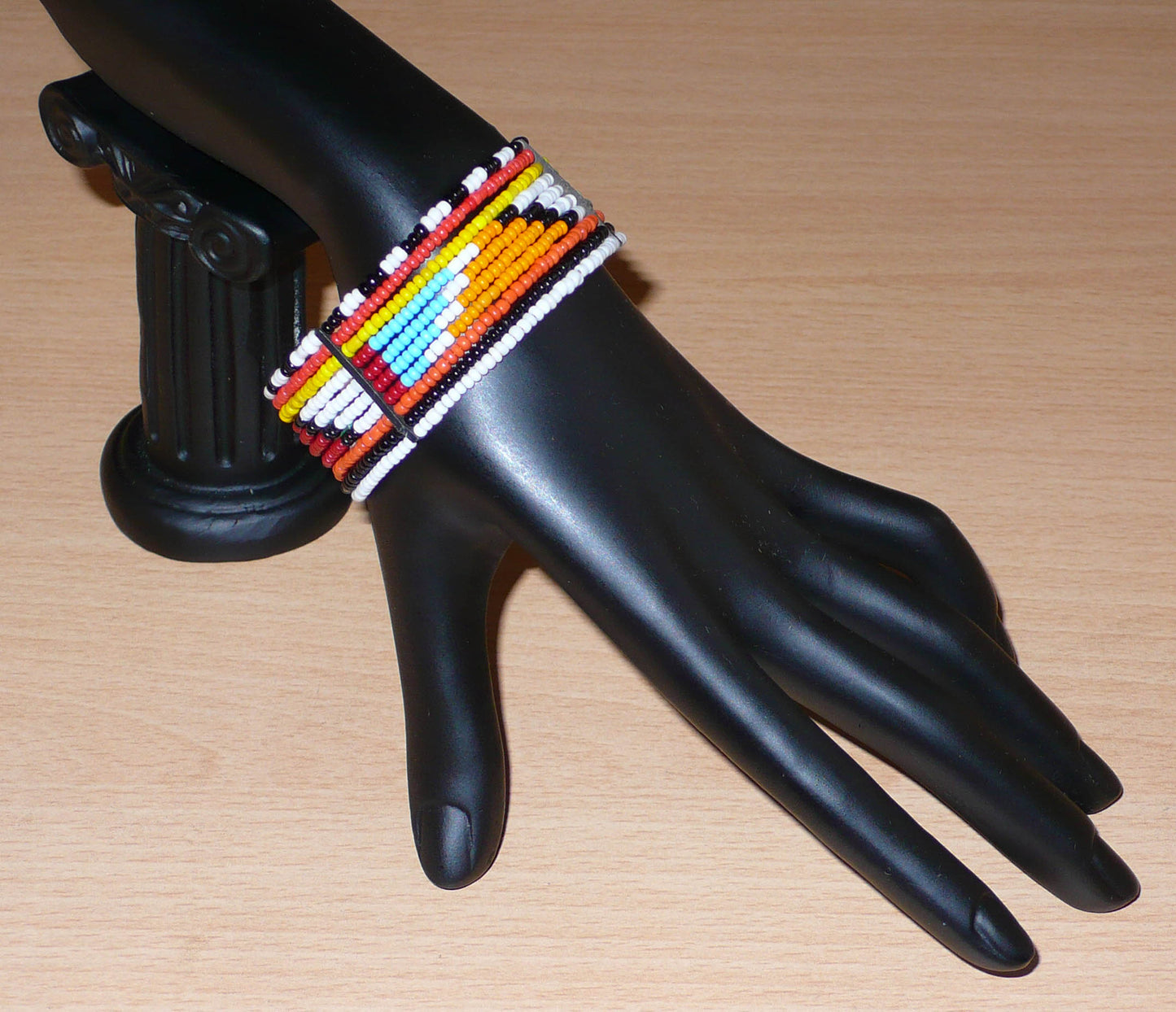 Bracelet africain tribal à motifs géométriques Massai fait de dix rangées de perles de rocaille multicolores enfilées sur des fils de fer fixés sur des charnières en plastique. Le bracelet se ferme avec des crochets.