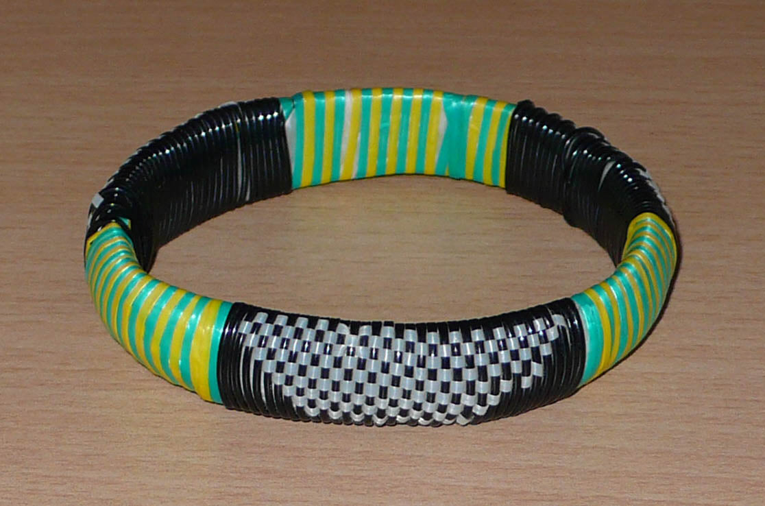 Bracelet africain eco-friendly tressé avec des fines bandes de plastique recyclé noir, blanc, vert et jaune.