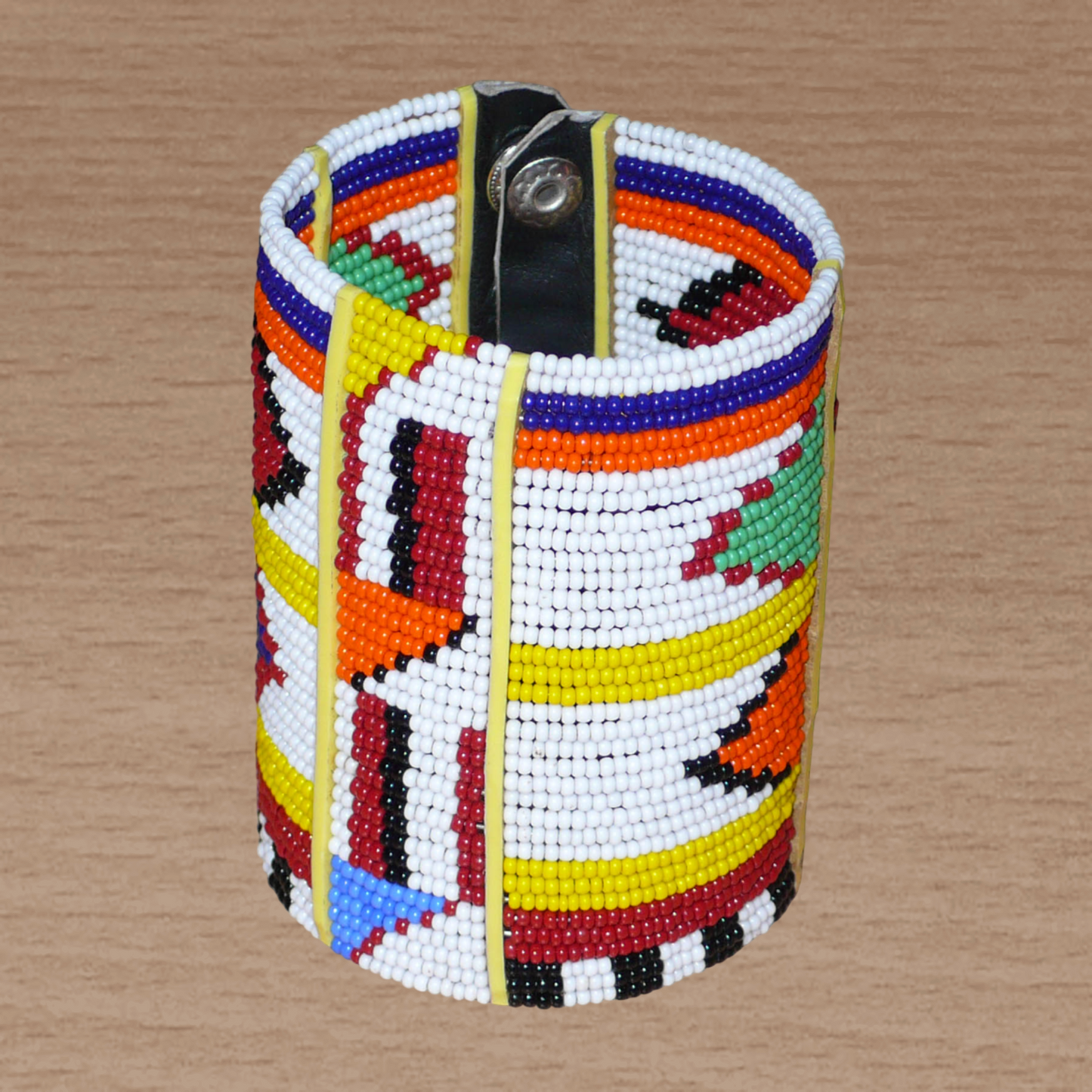Bracelet africain Massai multi-rangs à motifs ethniques composé de trente-six rangées de perles de rocaille blanches et multicolores glissées sur des fils de fer fixés sur des charnières en plastique jaune.