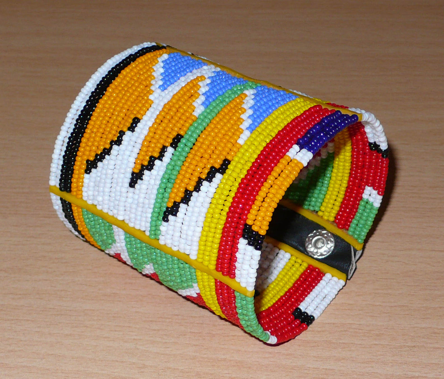 Bracelet africain tribal à motifs ethniques et géométriques Massai composé de perles de rocaille multicolores. Il s'attache avec trois boutons pressions.