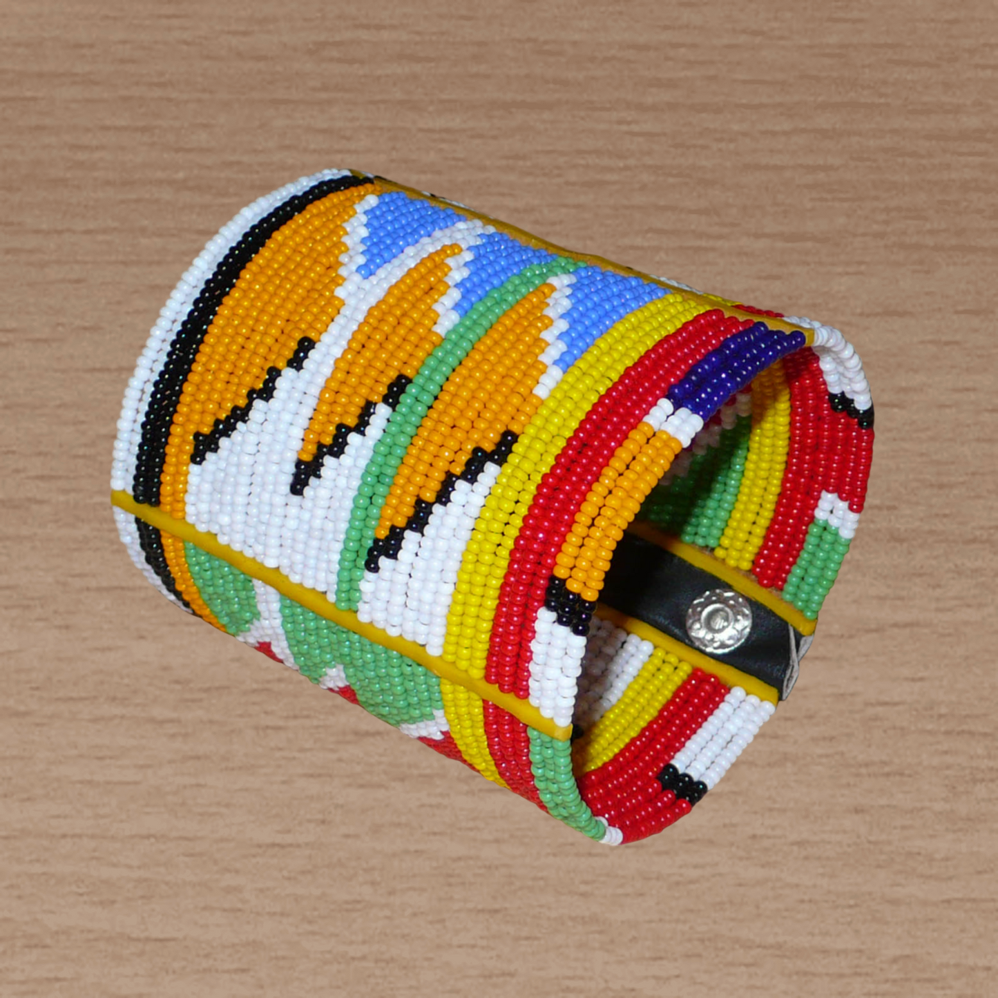 Bracelet africain tribal à motifs ethniques et géométriques Massai composé de perles de rocaille multicolores. Il s'attache avec trois boutons pressions.