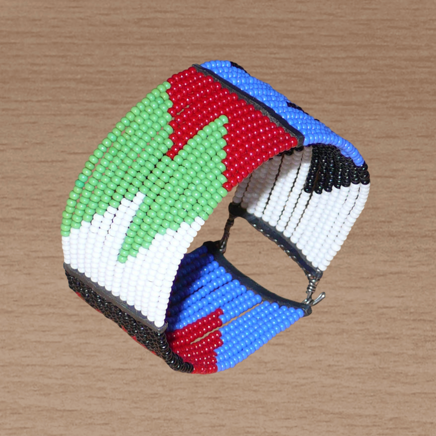 Bracelet africain Massai à motifs ethniques géométriques composé de quatorze rangées de perles de rocaille rouges, bleues, vertes, blanches et noires ; il s'attache avec deux crochets.