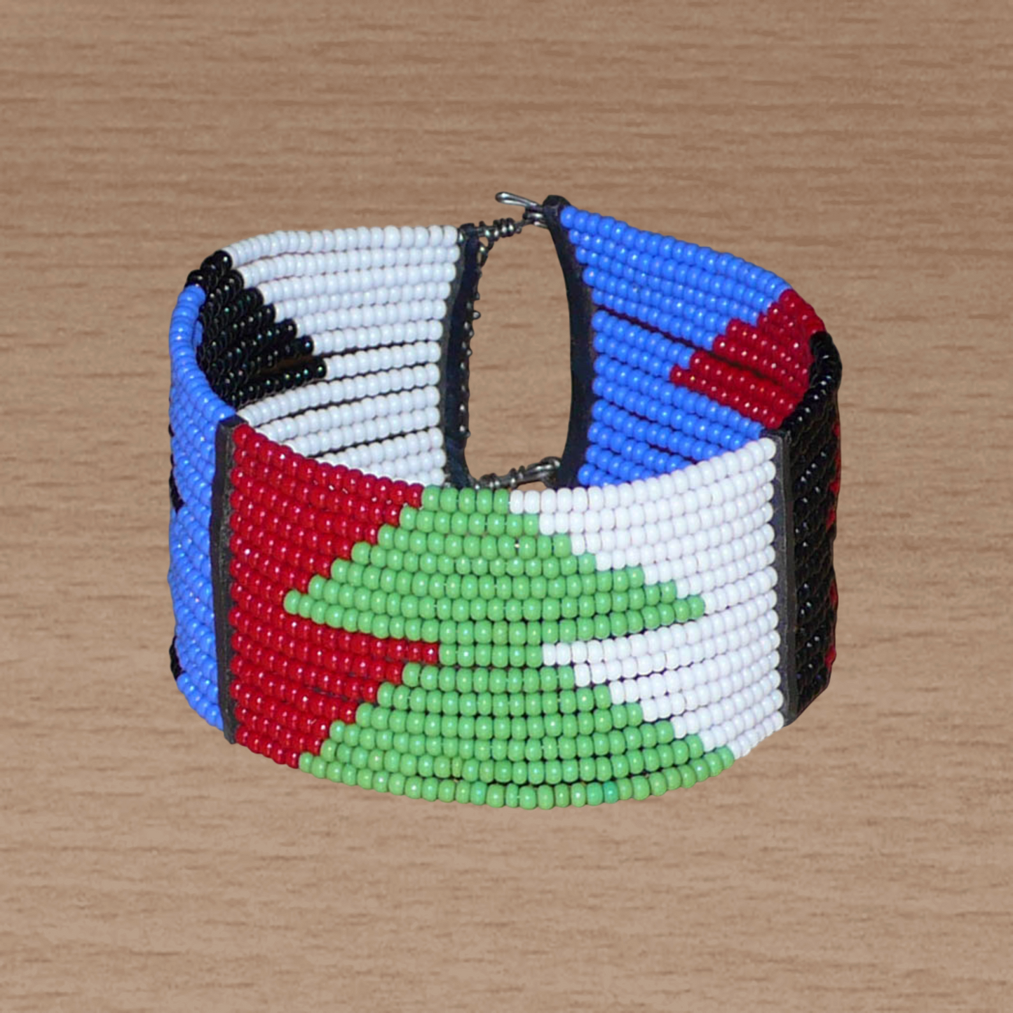 Bracelet africain Massai à motifs ethniques géométriques composé de quatorze rangées de perles de rocaille rouges, bleues, vertes, blanches et noires ; il s'attache avec deux crochets.