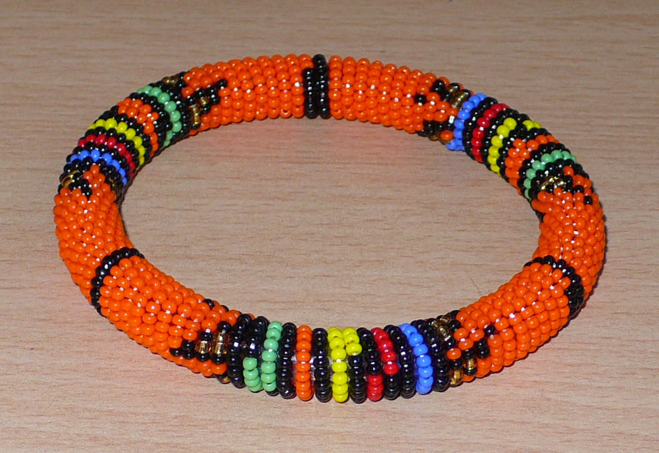 Bracelet africain traditionnel orange et multicolore à motifs ethniques zoulous composé de perles de rocaille tissées.