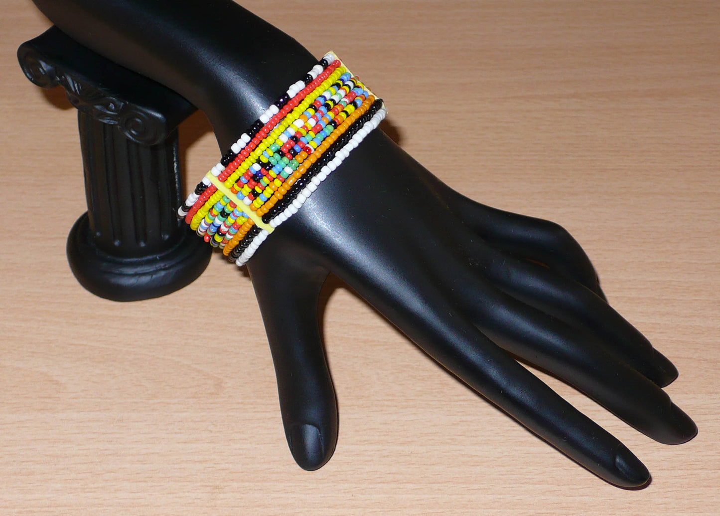 Bracelet africain Massai composé de dix rangées de perles de rocaille multicolores enfilées sur des fils de fer fixés sur des charnières en plastique. Le bracelet se ferme avec deux crochets.
