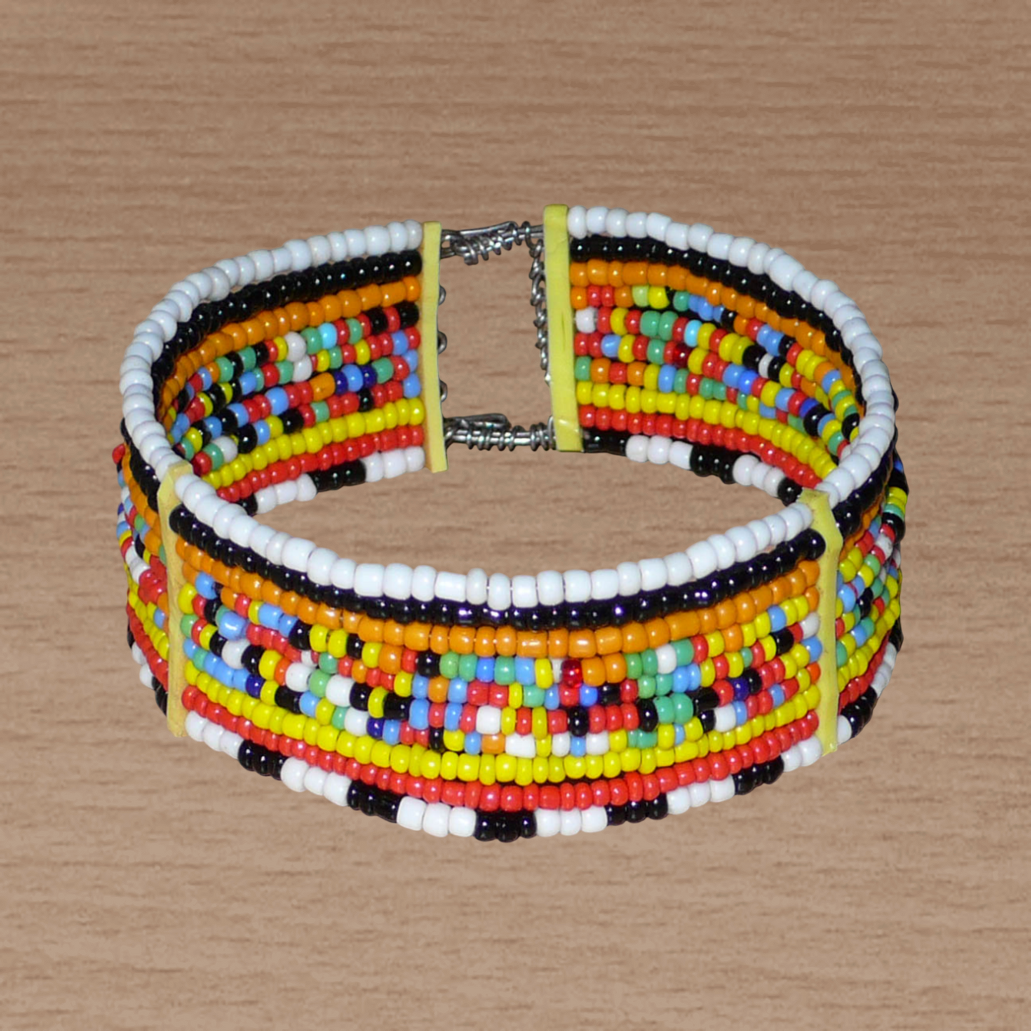 Bracelet africain Massai composé de dix rangées de perles de rocaille multicolores enfilées sur des fils de fer fixés sur des charnières en plastique. Le bracelet se ferme avec deux crochets.