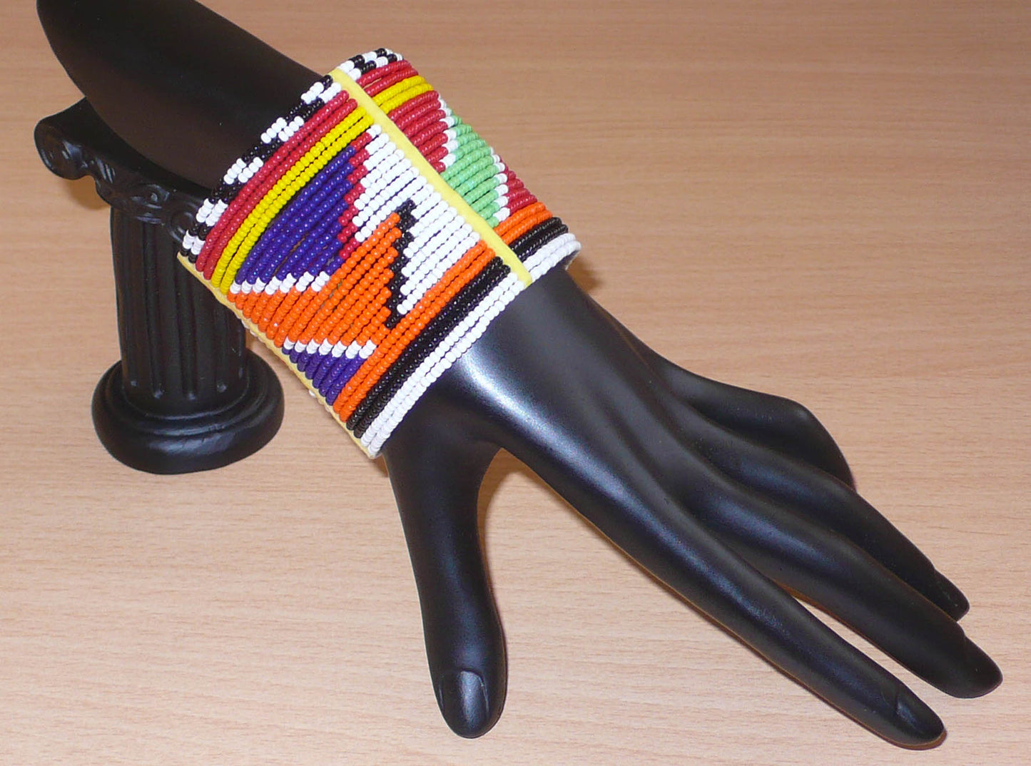 Bracelet africain traditionnel multi-rangs à motifs géométriques Massai composé de perles de rocaille multicolores enfilées sur vingt-six rangées de fils de fer fixés sur des charnières en plastique. Il s'attache avec des boutons pressions.